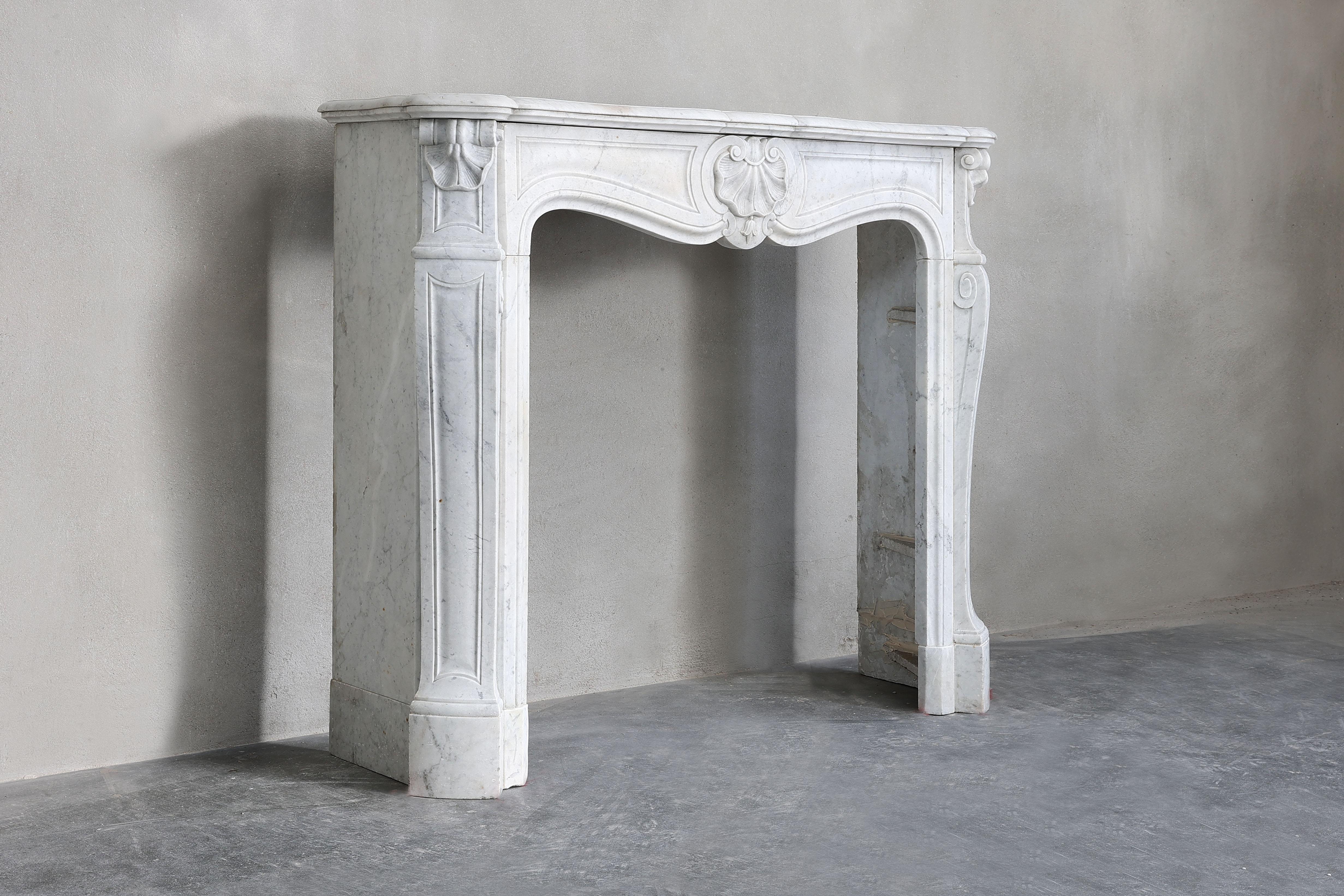 Beautiful antique fireplace of the Italian Carrara marble in the style of Louis XV. This chimney has a compact size, making it suitable for many interiors. The fireplace dates from the 19th century and is equipped with 'trois coquilles' and has