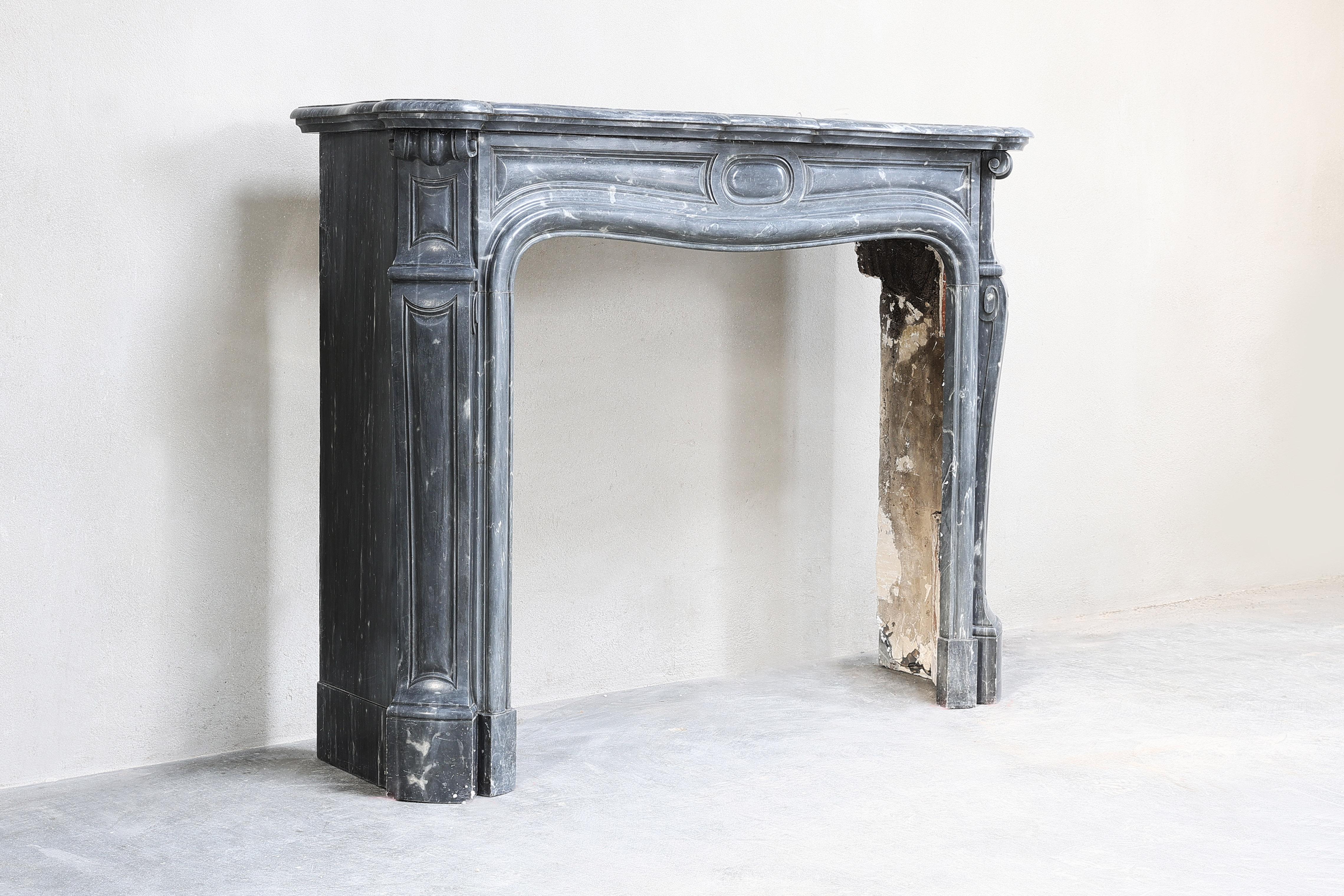 Beautiful antique fireplace made of blue turquin marble in pompadour style. This fireplace dates from the 19th century and has beautiful ornaments in the middle part and on the legs. The fossils and veins come into their own in this mantle! There