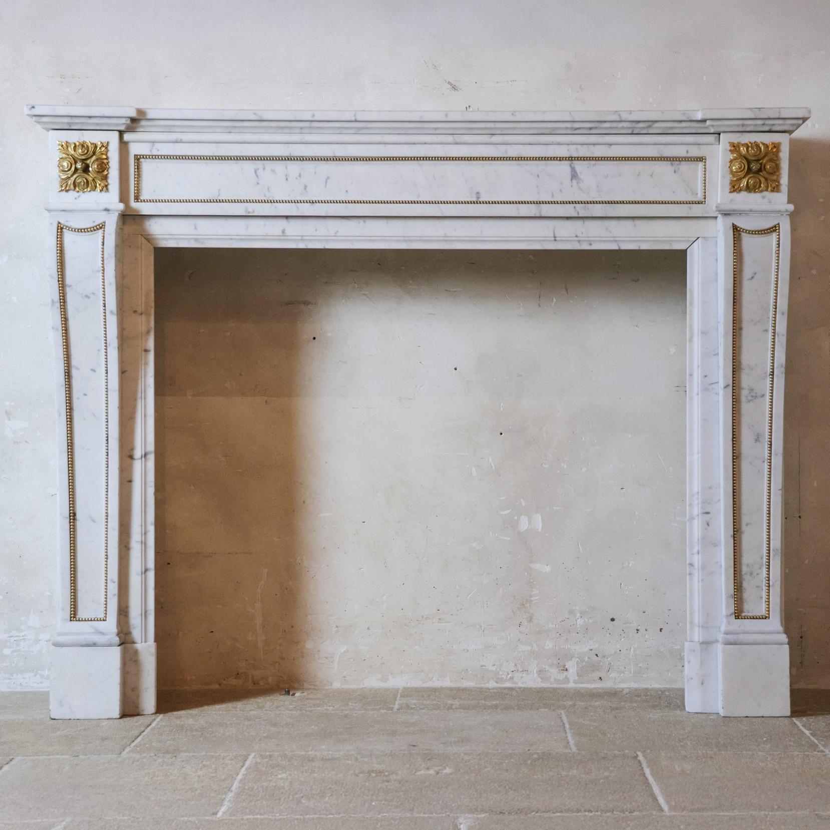 Antiker Marmorkamin aus weißem Carrara-Marmor mit feuervergoldeten Verzierungen, 19. Jahrhundert. Dieser antike Kamin aus dem 19. Jahrhundert ist aus hochwertigem Marbre Blanc de Carrare gefertigt, der für seine klare, reinweiße Farbe und seine