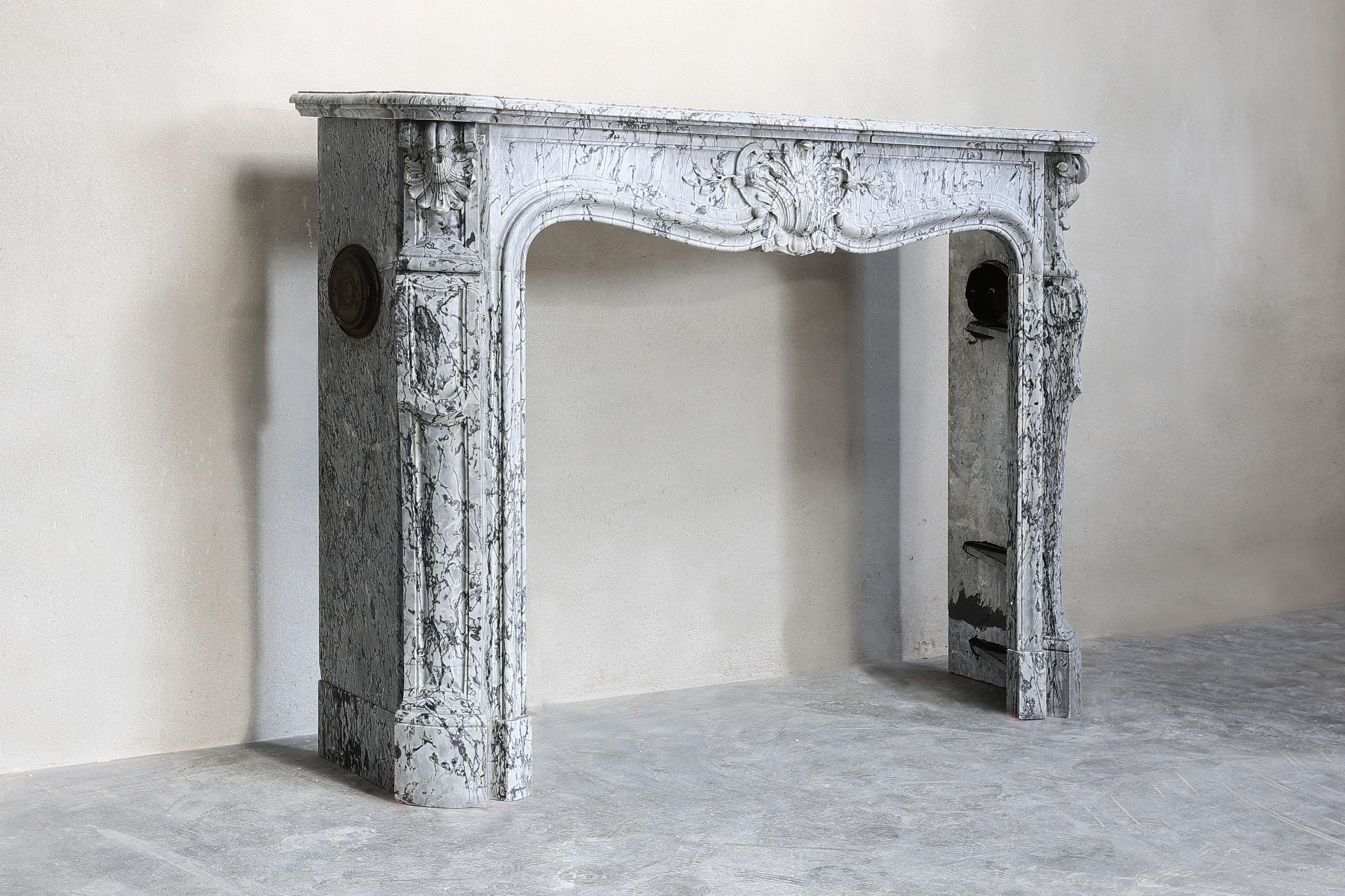 Beautiful antique fireplace of blue Fleuri marble from the 19th century in Louis XV style. This chimney is equipped with 'trois scallops' and has beautiful lines! The ornaments and naturally formed veins also make this fireplace very special!