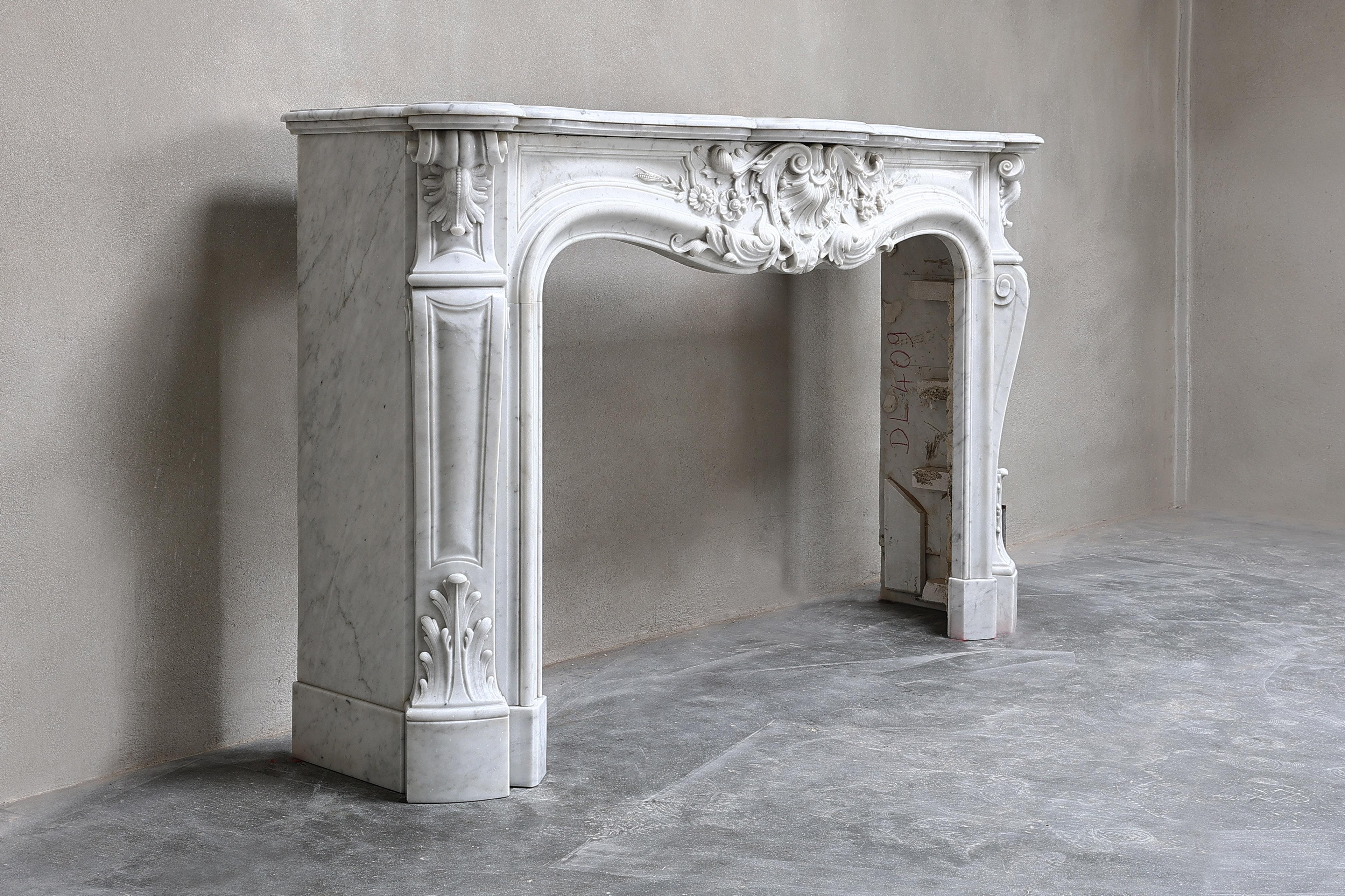 Beautiful exclusive antique fireplace made of Carrara marble from Italy! This 19th century fireplace is in the style of Louis XV and richly decorated with various ornaments in the front part and on the legs. A chic fireplace within our collection.