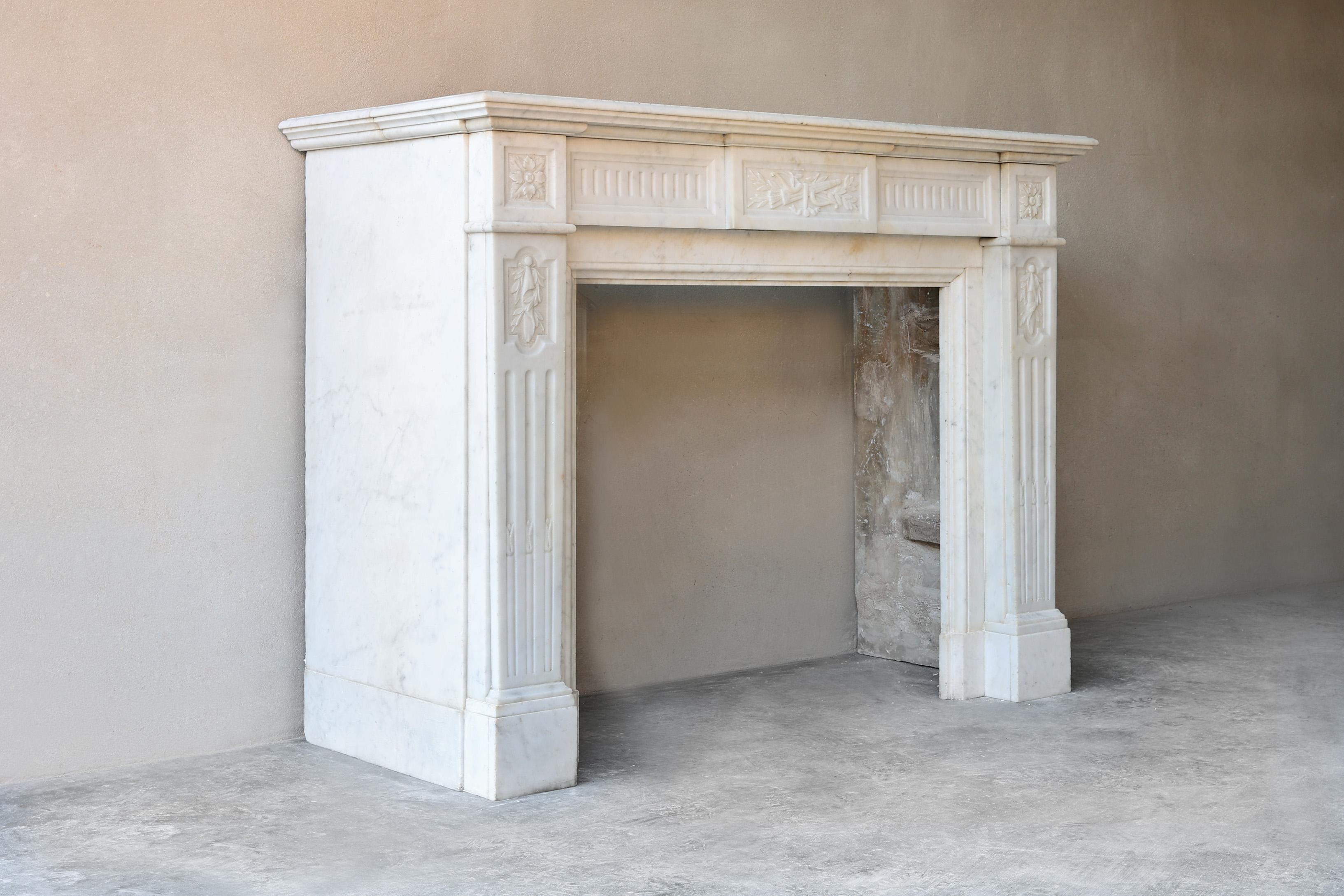 Very beautiful antique fireplace that is richly decorated with decorative elements and therefore has an elegant appearance. This Carrara marble mantel dates from the 19th century and is in the style of Louis XVI. A straight fireplace with various