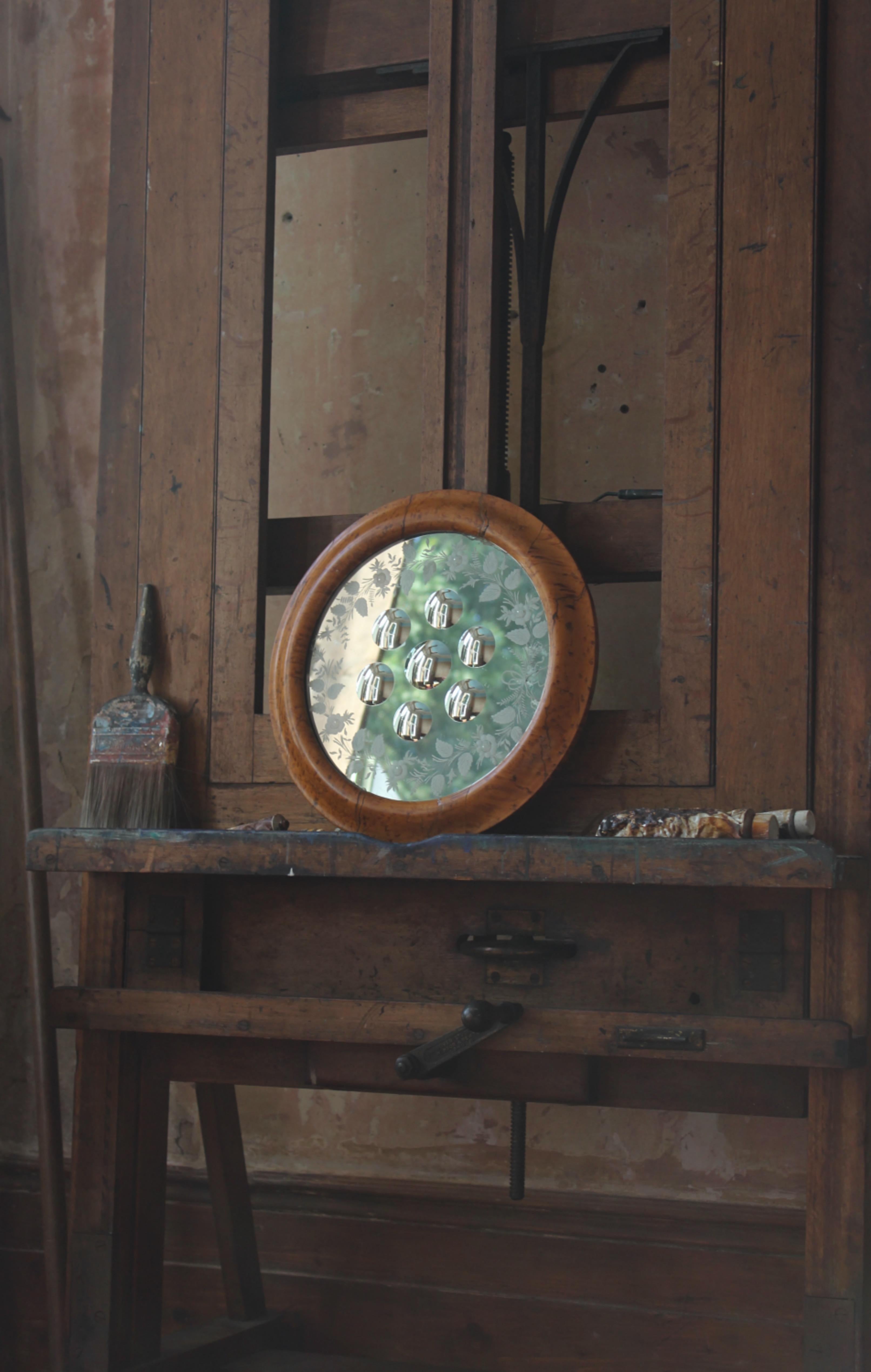 Un grand miroir de sorcière de la fin du XIXe siècle, logé dans un cadre ovale plaqué d'érable, avec sept optiques convexes à fond inversé. La partie extérieure du miroir est ornée d'un feuillage gravé à l'acide. 38 cm de diamètre.

Quelques petites