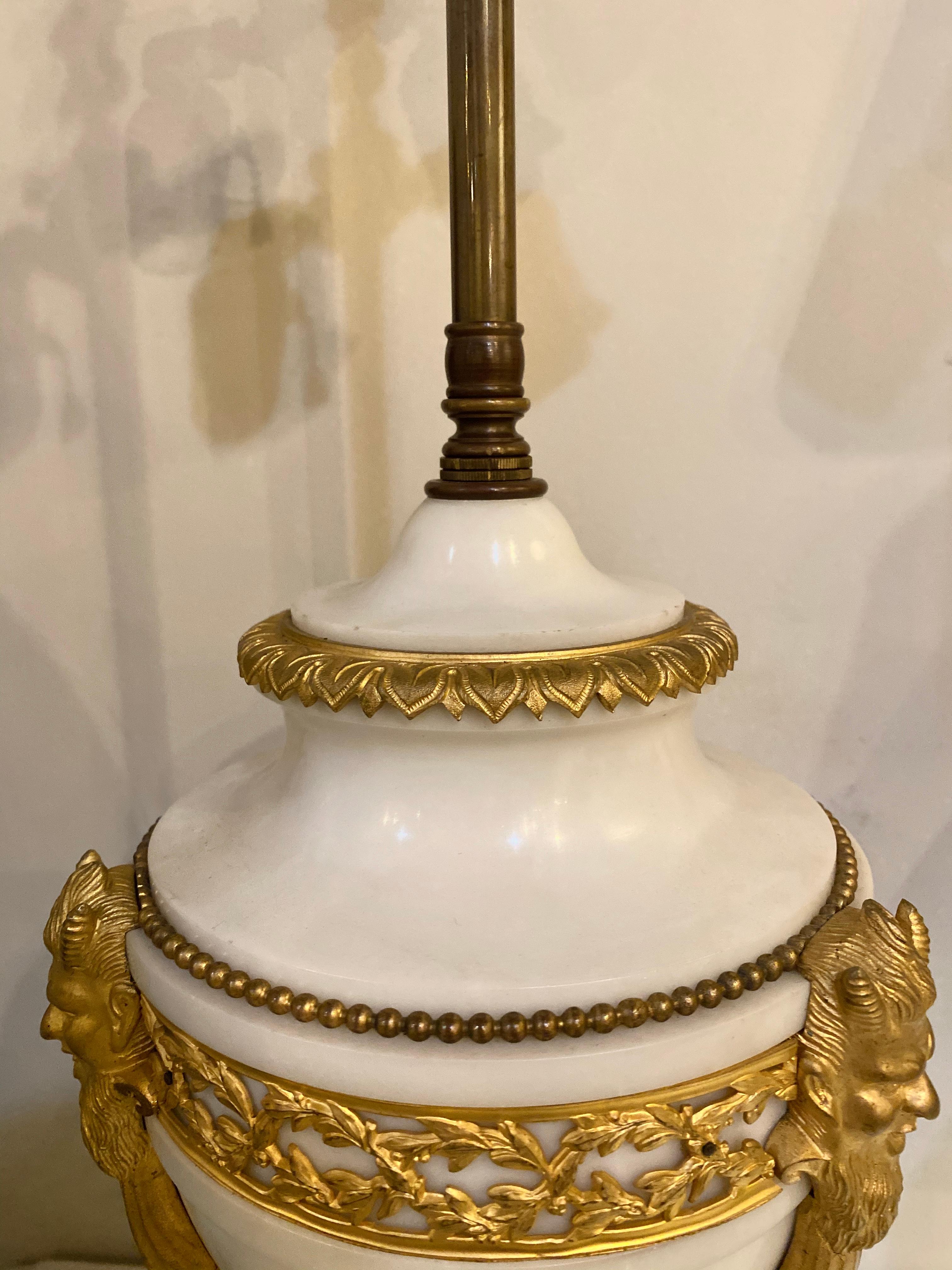 Marble and bronze table lamp with custom shade. A finely crafted doré bronze and marble urn depicting satirical horned heads mounted onto the bronze framed marble urn. The whole having a spectacular custom shade. The lamp itself taking two light