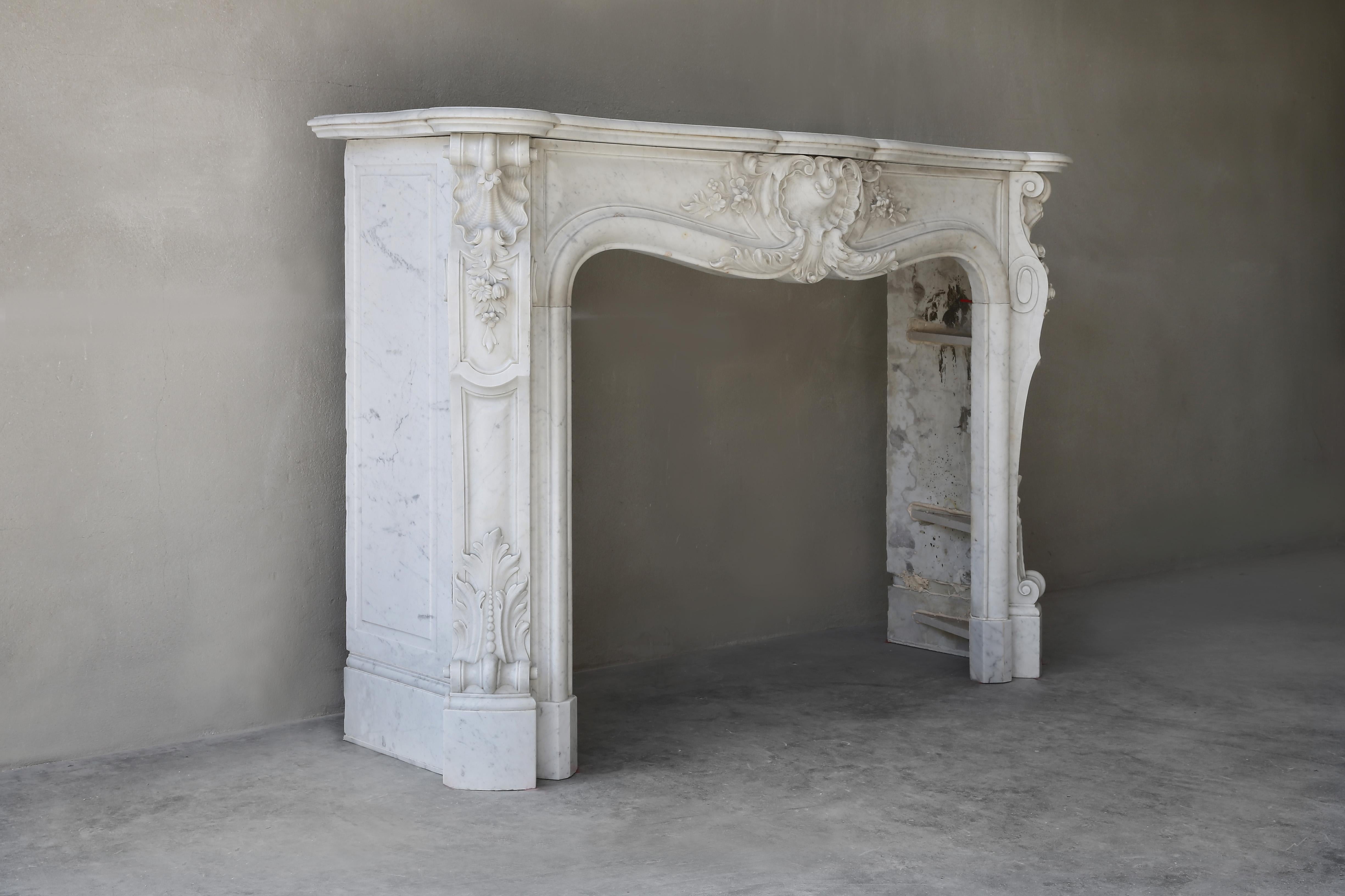 Very beautiful antique fireplace in Carrara marble from the 19th century in the style of Louis XV. A fireplace with beautiful decorations and ornaments, a scallop in the middle and on the legs. A special mantel (fireplace) with Fine chiselling and