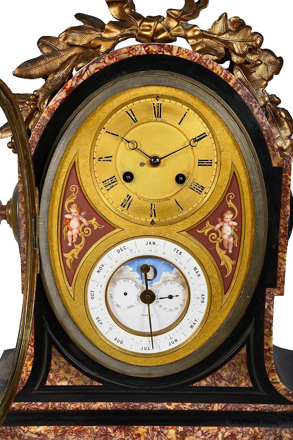 Pendule de manteau en marbre noir et rouge de très bonne qualité du 19ème siècle avec calendrier. La partie supérieure est ornée d'une monture en bronze doré et d'un cadran doré avec un mouvement à sonnerie de huit jours, d'une heure et d'une
