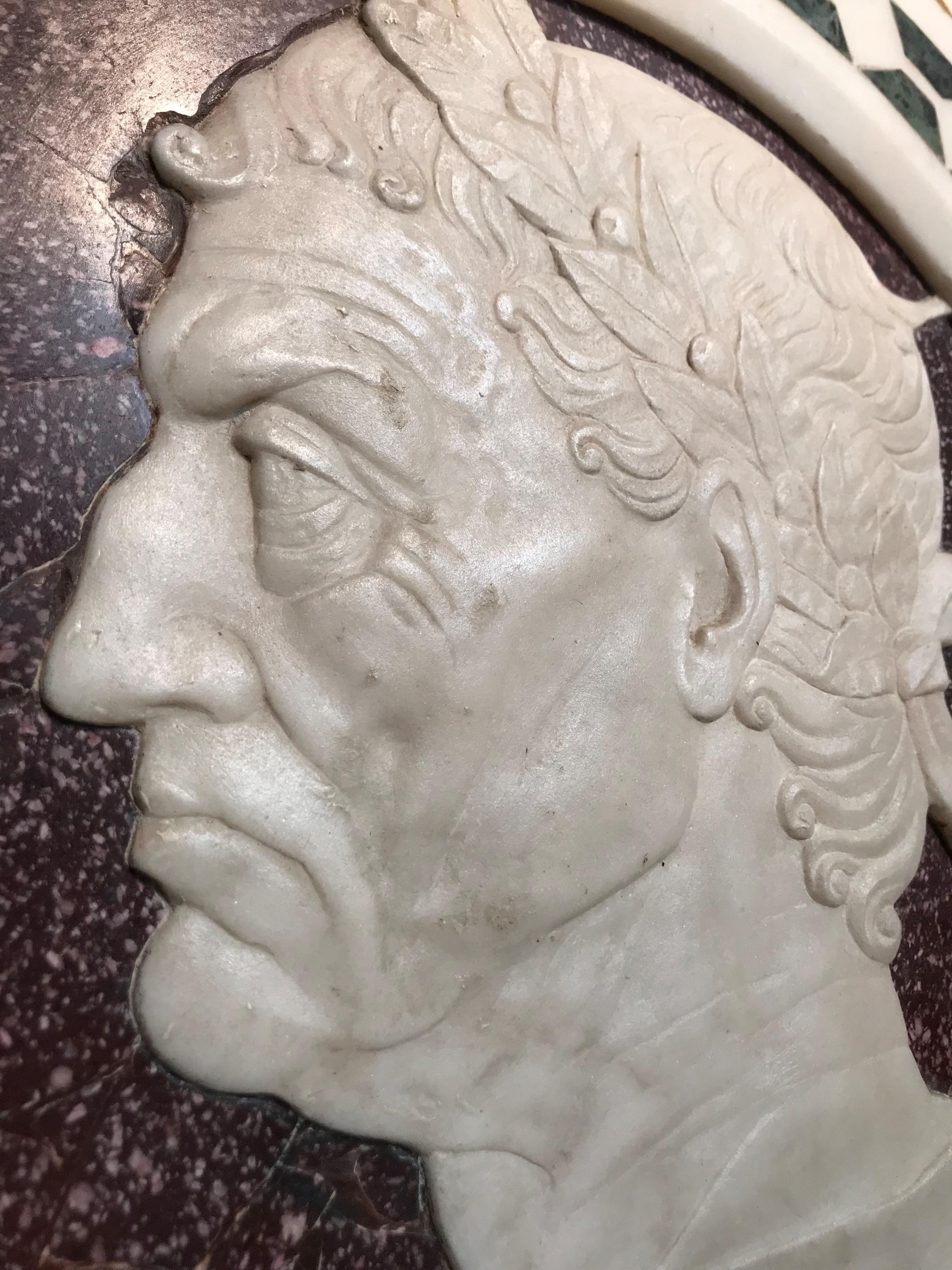 An Italian circular colored marble and porphyry relief showing the profile in white marble of a Roman emperor on a red porphyry background. The frame is inlaid with green and yellow Sienna marble.  Late 18th - Early 19th Century.