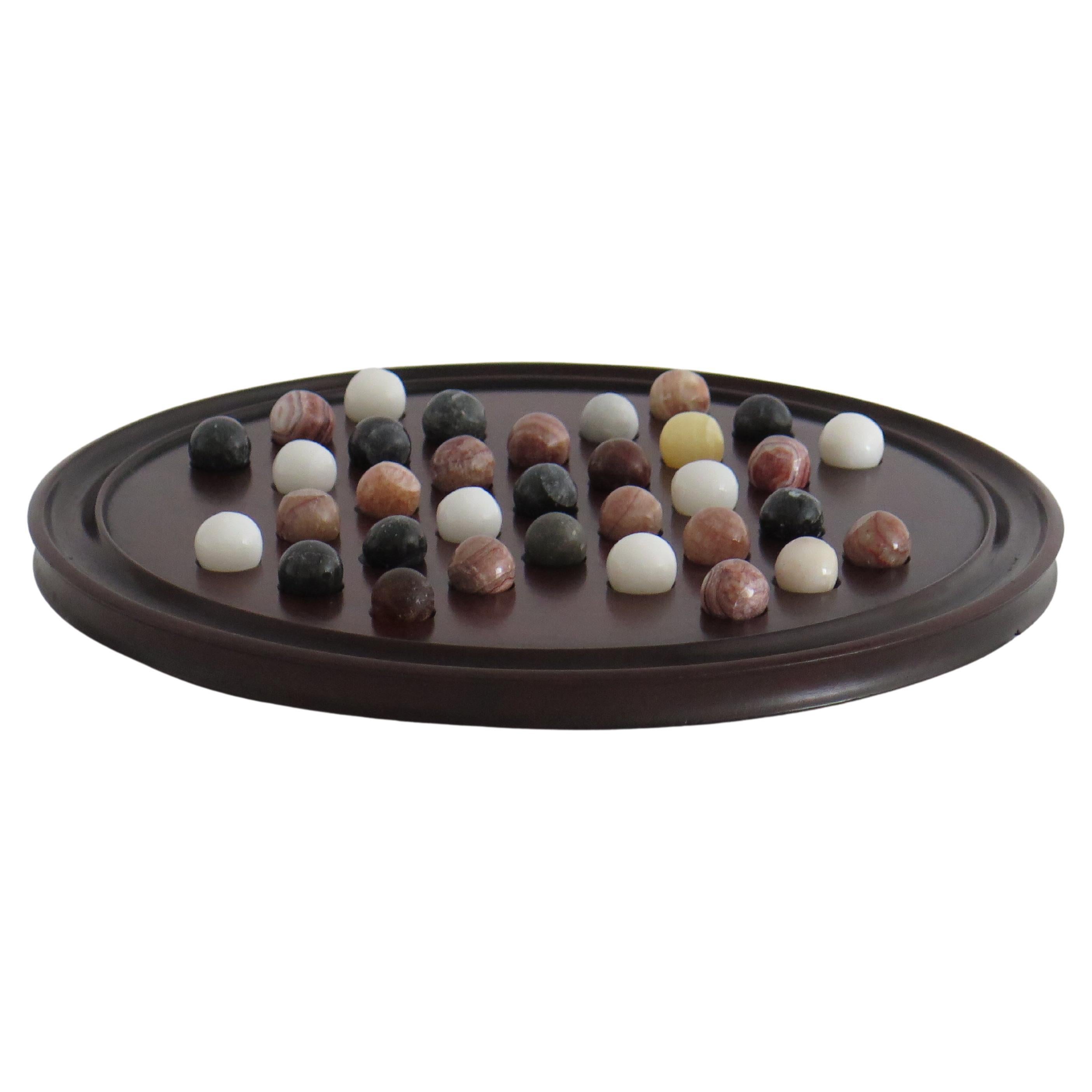 This is a complete late Victorian board game of table marble solitaire, with a lovely hand turned large hardwood board and 33 early agate stone hand made marbles, all dating to the late 19th century. 

The circular board has a larger than normal