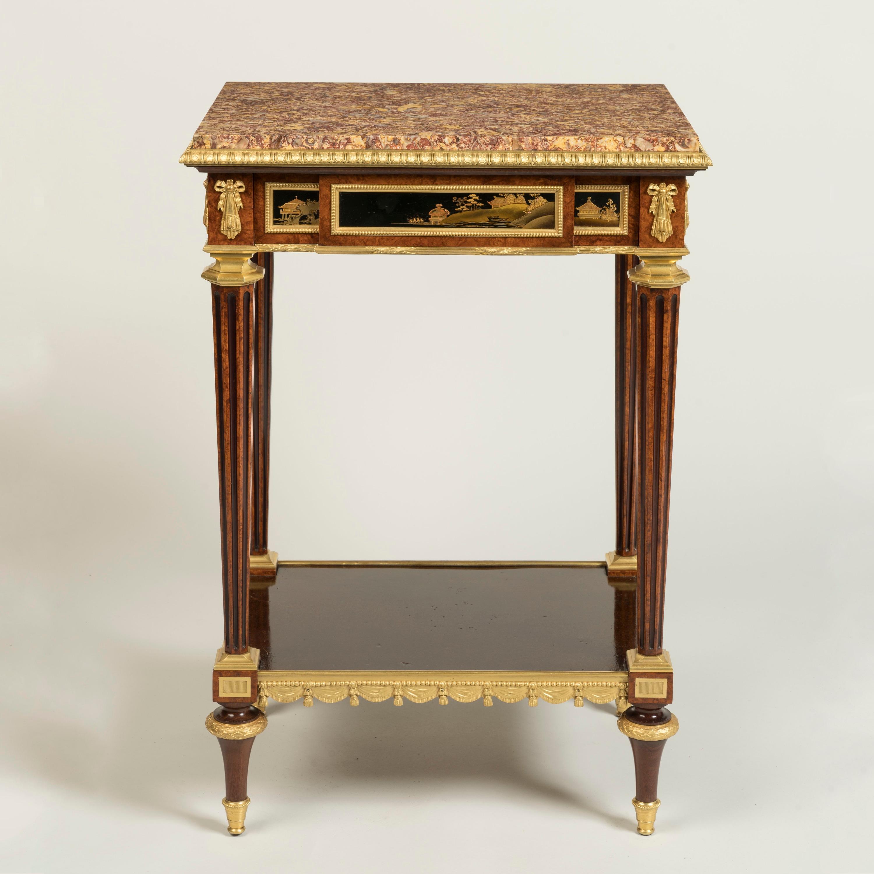 Of rectangular form, constructed in amboyna and mahogany dressed with chinoiserie lacquer panels, and fine ormolu mounts; rising from ormolu mounted toupie feet, supporting the lower platform finished with aventurine gold speckled lacquer, itself