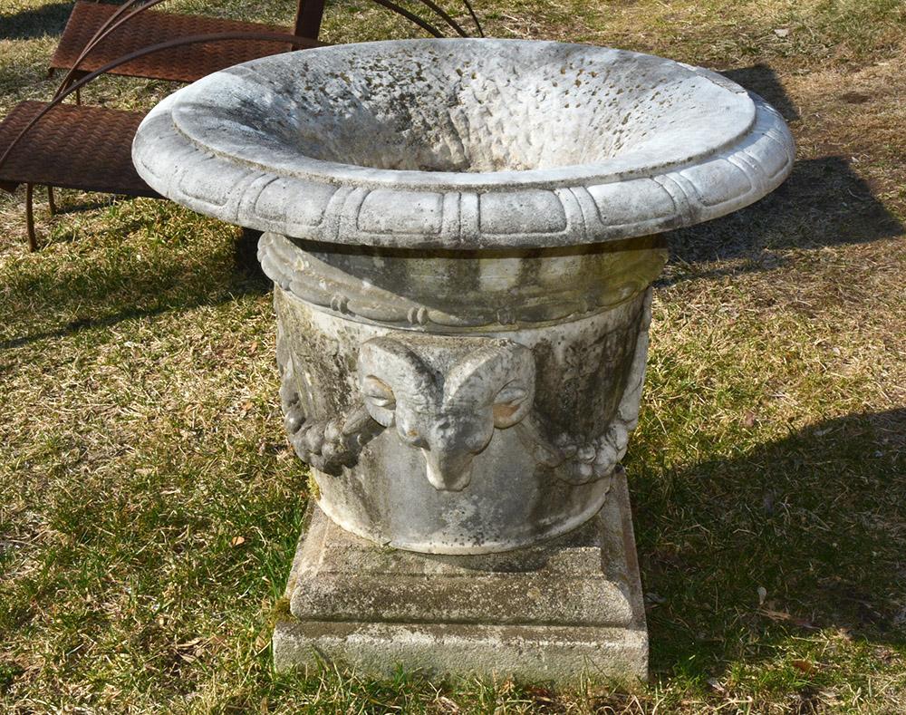 Impressive 19th century marble urn with beautifully carved ram heads and draped Garland. The urn sits on a 20th C. concrete base. The rim of The urn has a very old repair .
 