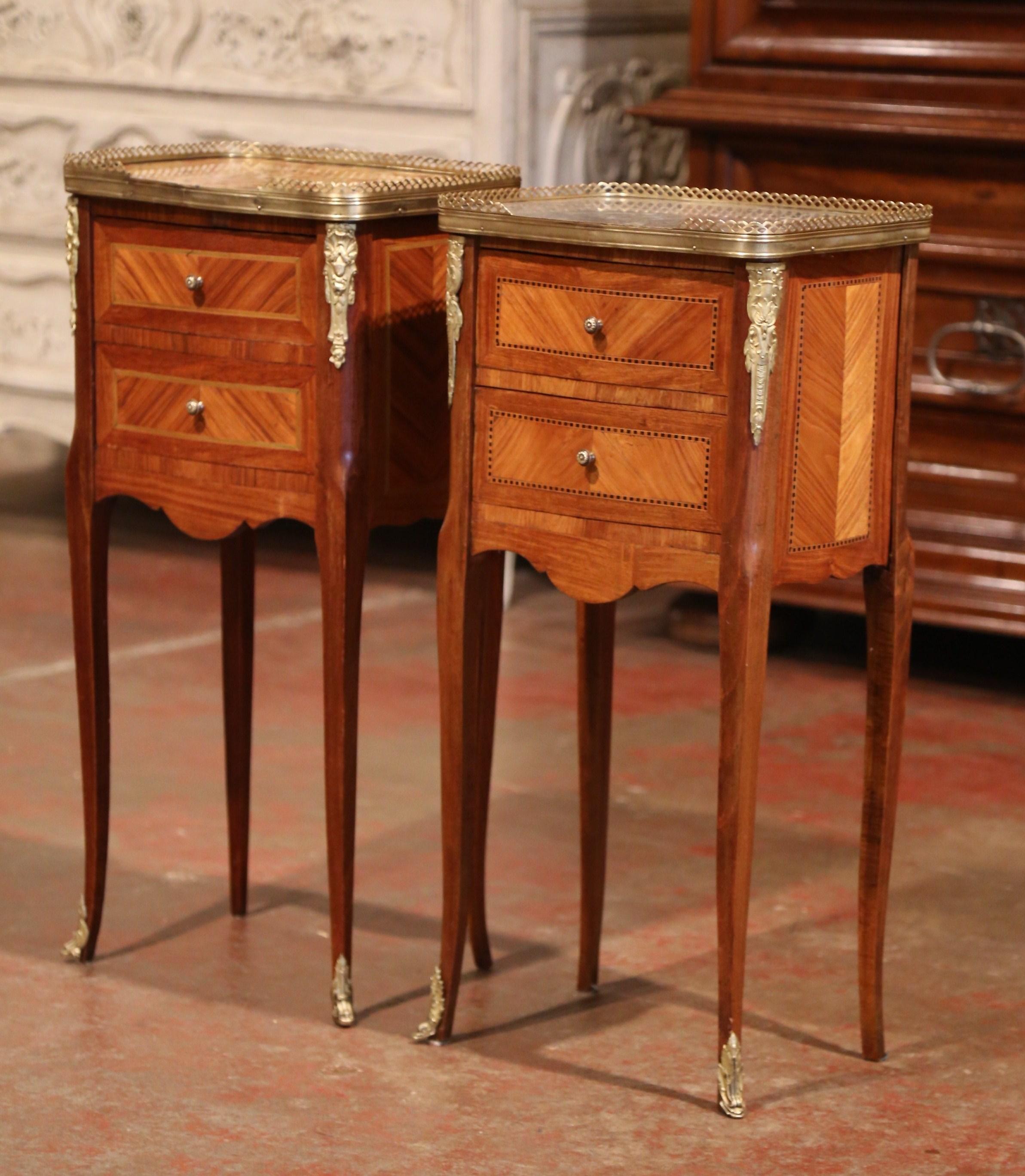 Crafted in France circa 1890, these elegant antique chests stand on cabriole legs decorated with bronze caps feet over a scalloped apron. The petite Louis XV style commodes feature two drawers across the front decorated with marquetry inlay work and