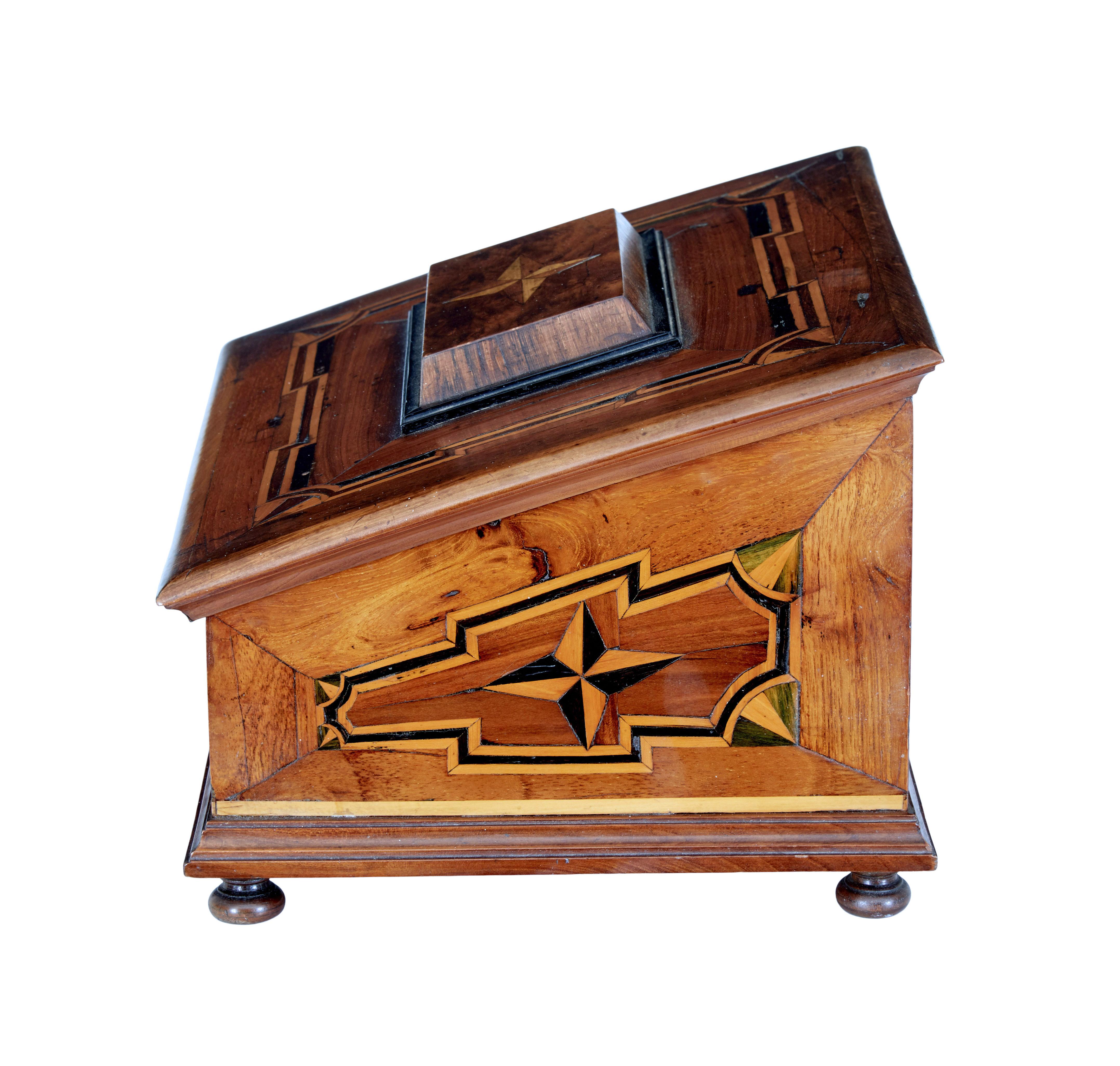 19th century marquetry fruitwood desktop box circa 1890.

Good quality desktop box covered with marquetry on all surfaces. Sloped front with decorative star panel.  Top opens to reveal a partially fitted interior, containing a candle box or for