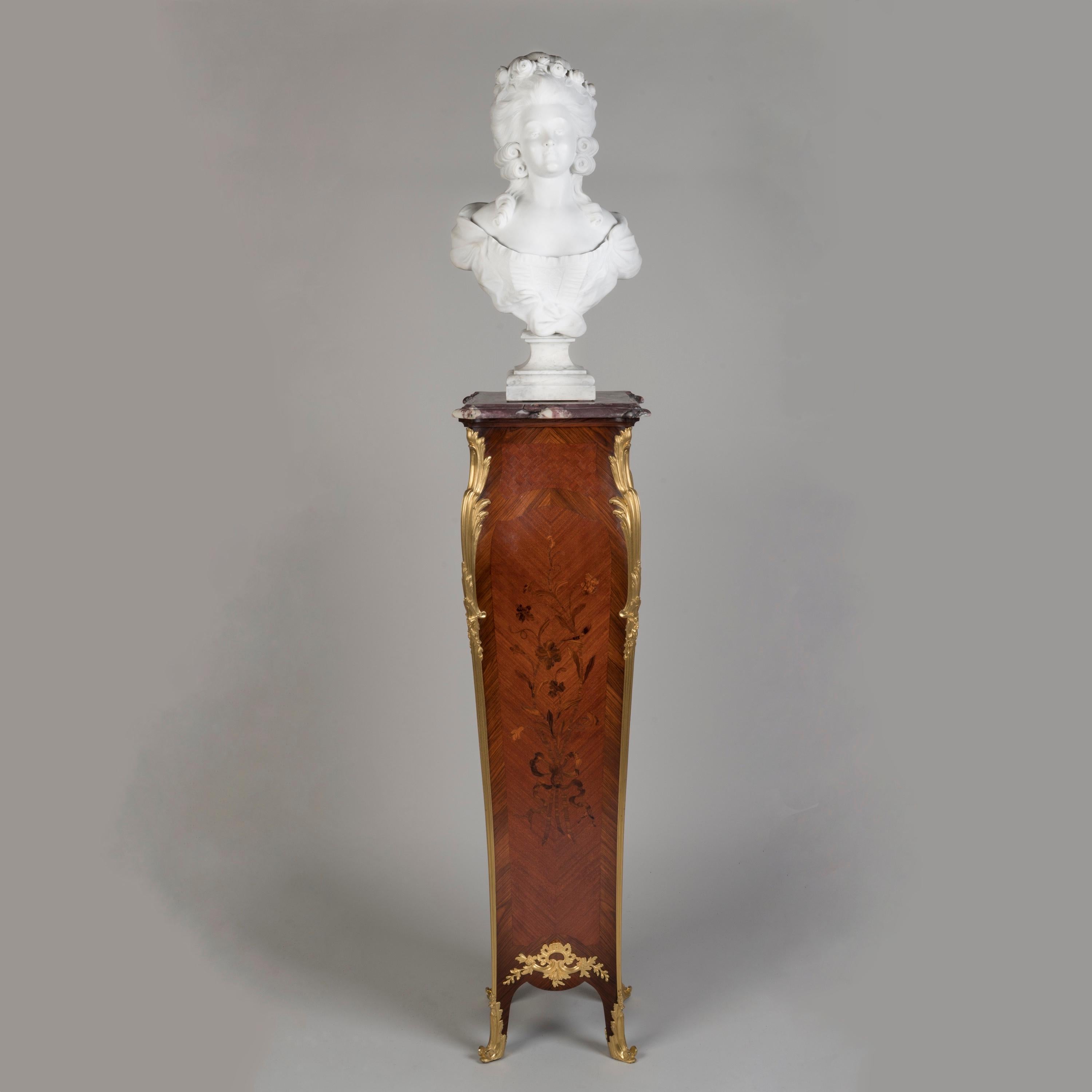 An Elegant Marquetry Pedestal
By Maison Millet of Paris

Of elegant bombé form with bookmatched kingwood crossbanding and a bois de bout floral marquetry panel on a bois satiné ground, the corners dressed with acanthus ormolu mounts terminating
