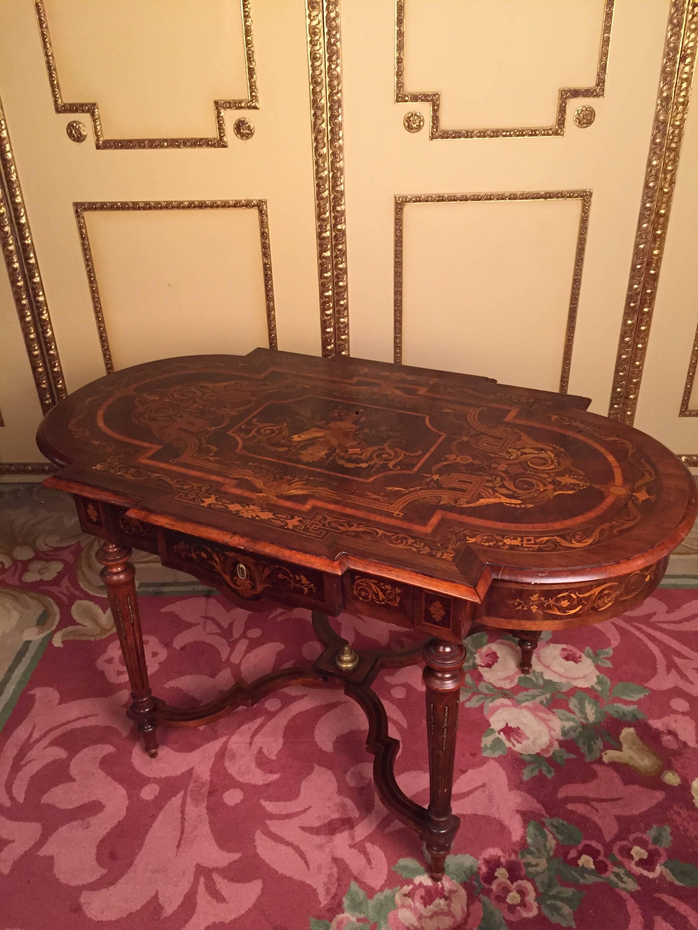 Rectangular with semi-circular sides.
The body stands on conical legs, which are connected to a cross-bridge. Tabletop strongly inlaid with tendrils and foliage.

A drawer with key.
Marketerie with precious wood:
Mahogany and tulip


(A-134).