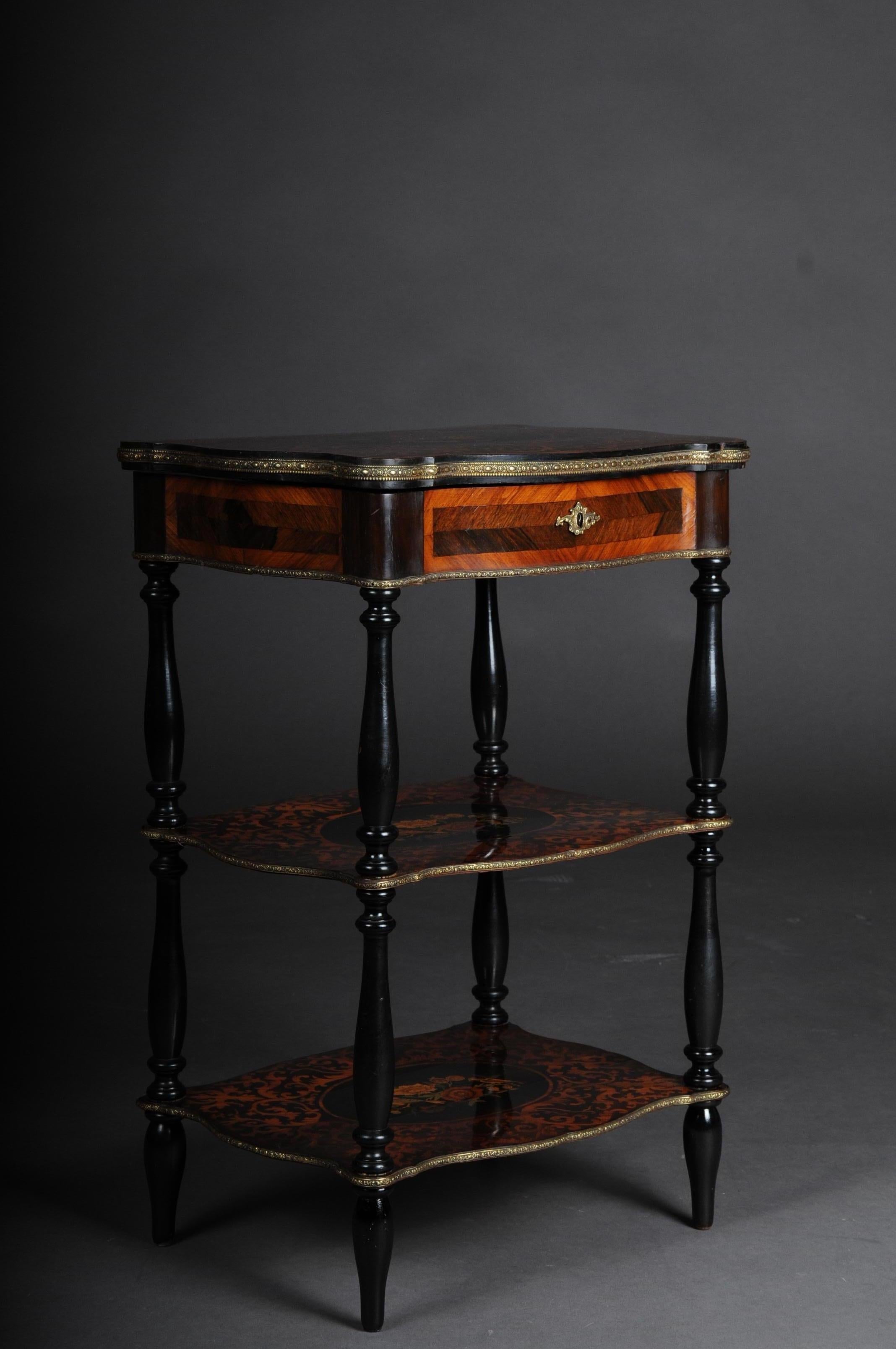 19th century Marquetry side table with jewelry box circa 1870

3-tier side table with decorative key function. Solid wood with exotic inlays, partially ebonized. Rectangular body framed with brass fittings flanked by 4 blackened full columns.