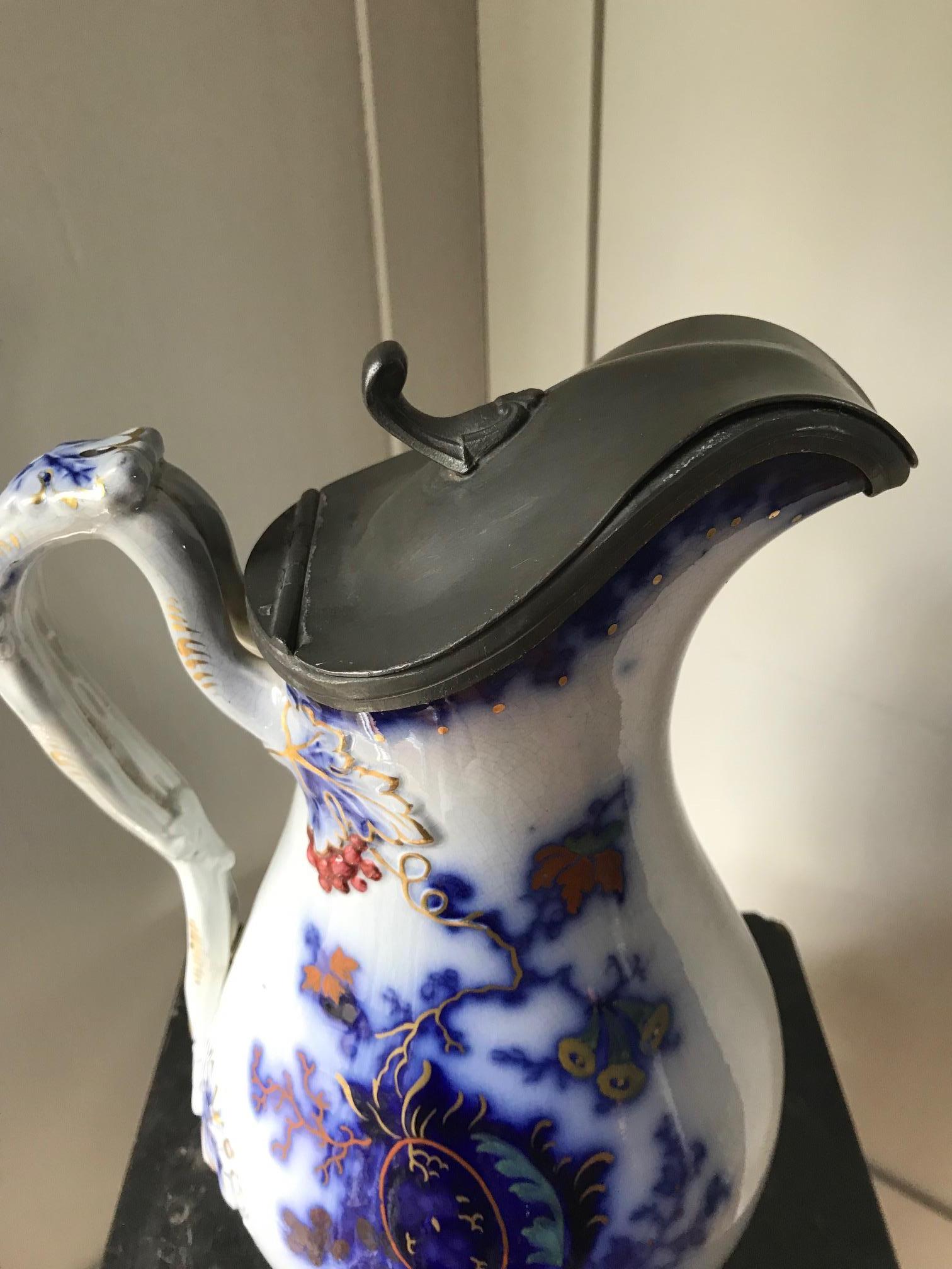An attractive lidded Chinese Masons stone pitcher ornately decorated with blue intricate floral motifs of Chinese taste. Hinged with a pewter lid.