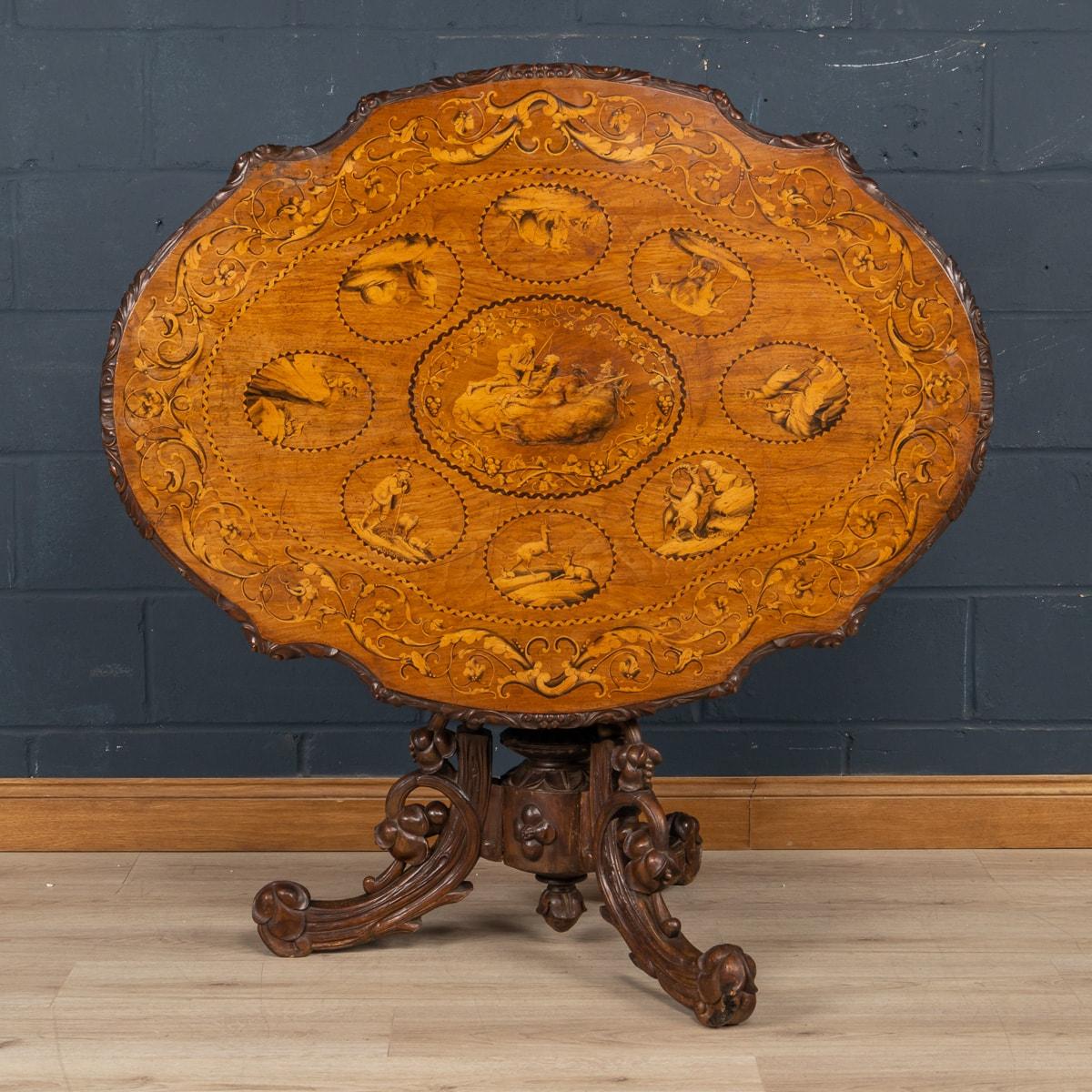 An exceptional Swiss Black Forest walnut marquetry tilt-top table The shield form table top, with a marquetry inlay presenting superb examples of original pen-work, and carved apron supported by an intricately carved tripod base. What sets this pice