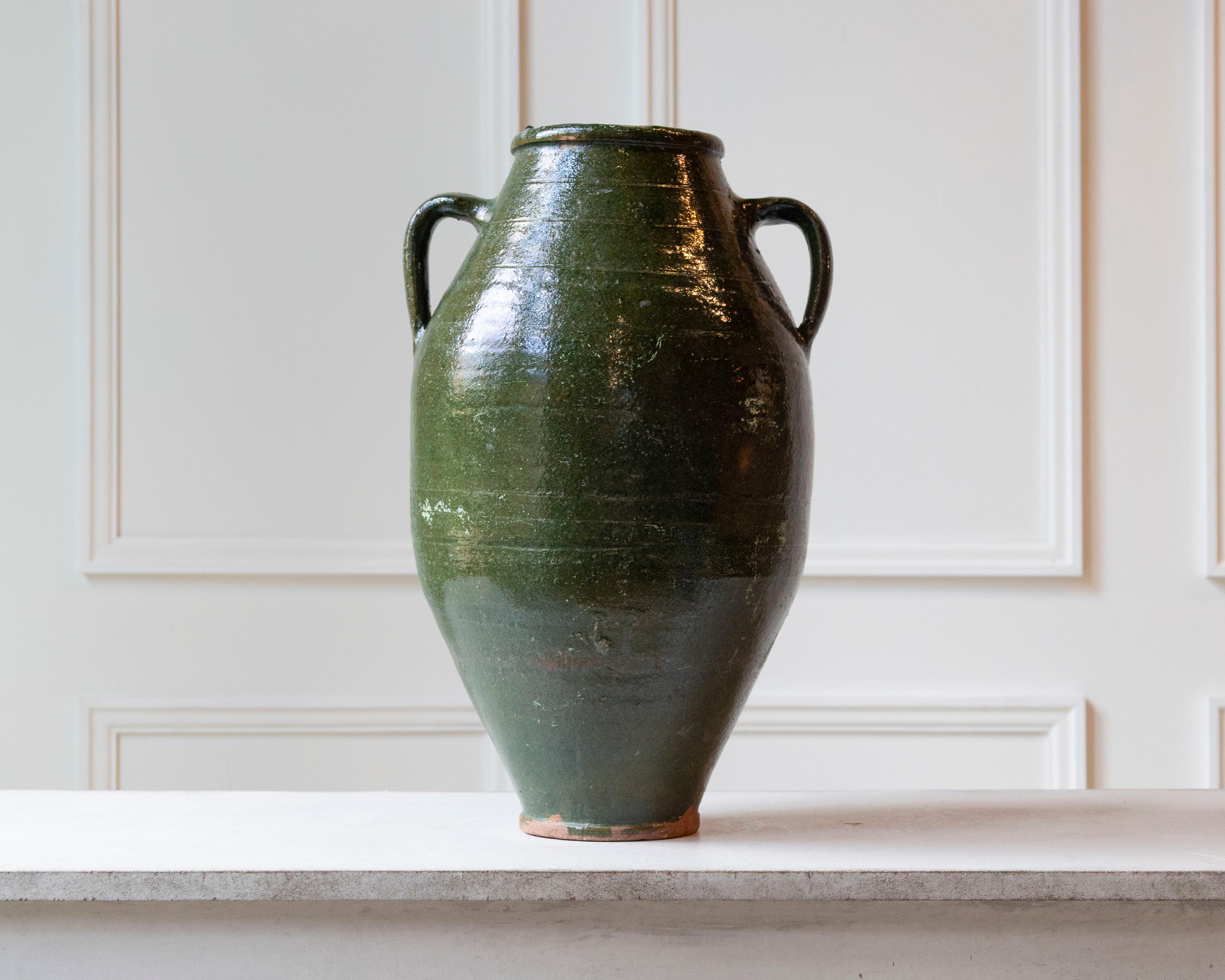 This beautiful 19th-century Mediterranean terracotta jar features a graceful baluster form, glazed in a richly saturated olive green that evokes the tones of ancient earthenware from Southern Europe. With its high shoulders and narrow foot, the