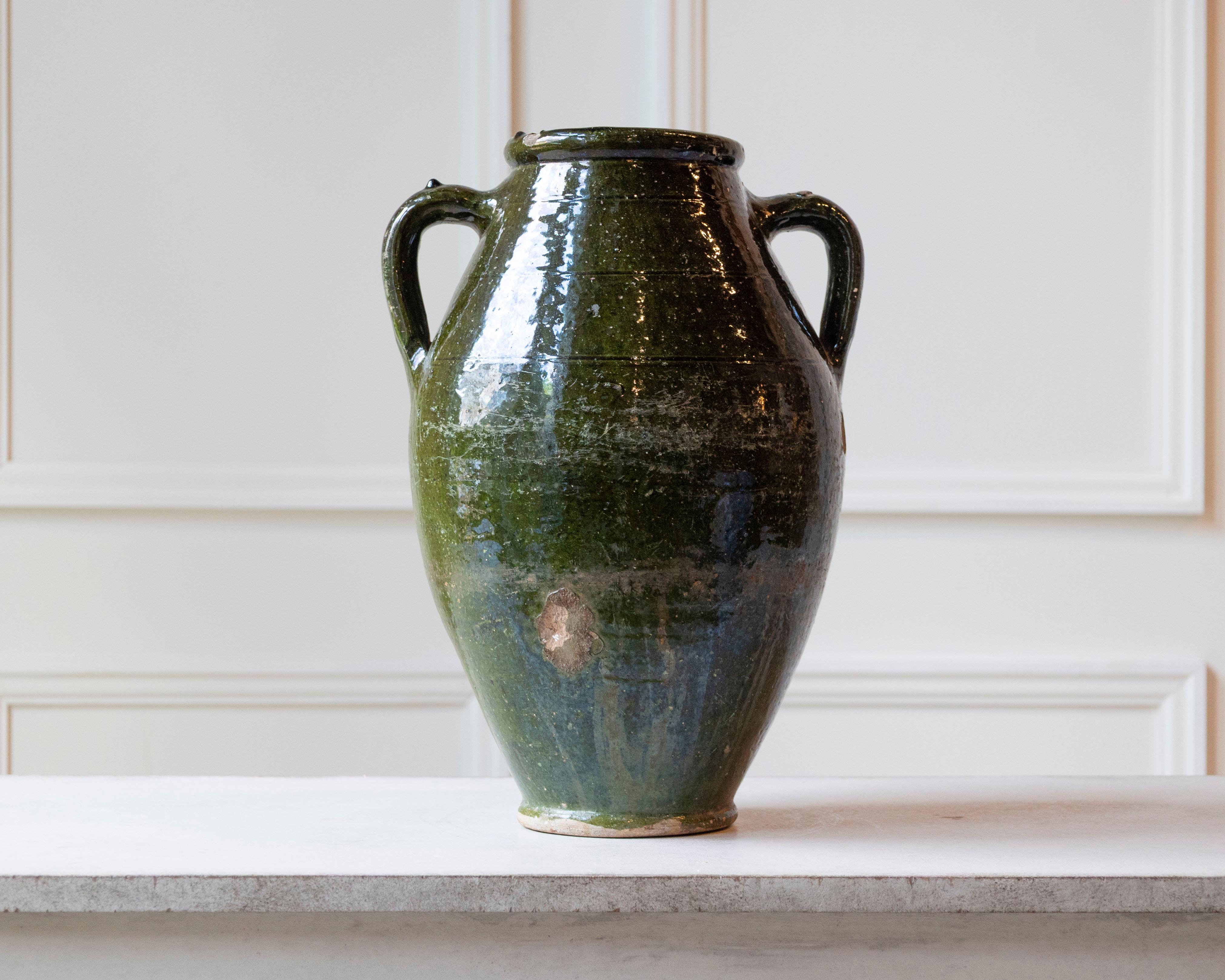 This stunning 19th-century Mediterranean terracotta jar features a graceful baluster form, glazed in a richly saturated olive green that evokes the tones of ancient earthenware from Southern Europe. With its high shoulders and narrow foot, the piece