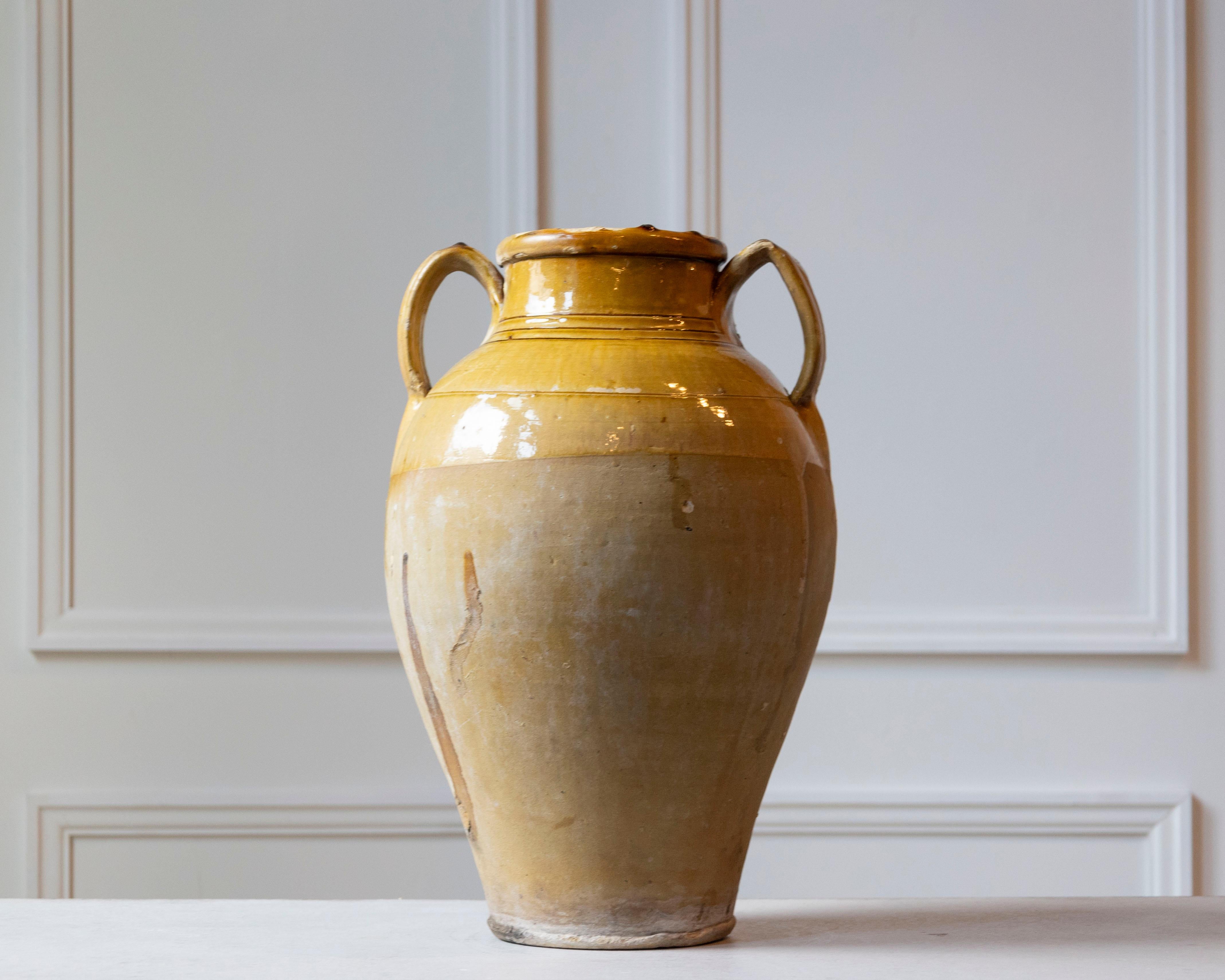 Una vivace brocca in ceramica mediterranea del XIX secolo con un ricco smalto giallo oro che evoca immediatamente il calore e la luce del sole dell'Europa meridionale. Probabilmente originario della Provenza o della Catalogna, questo recipiente di