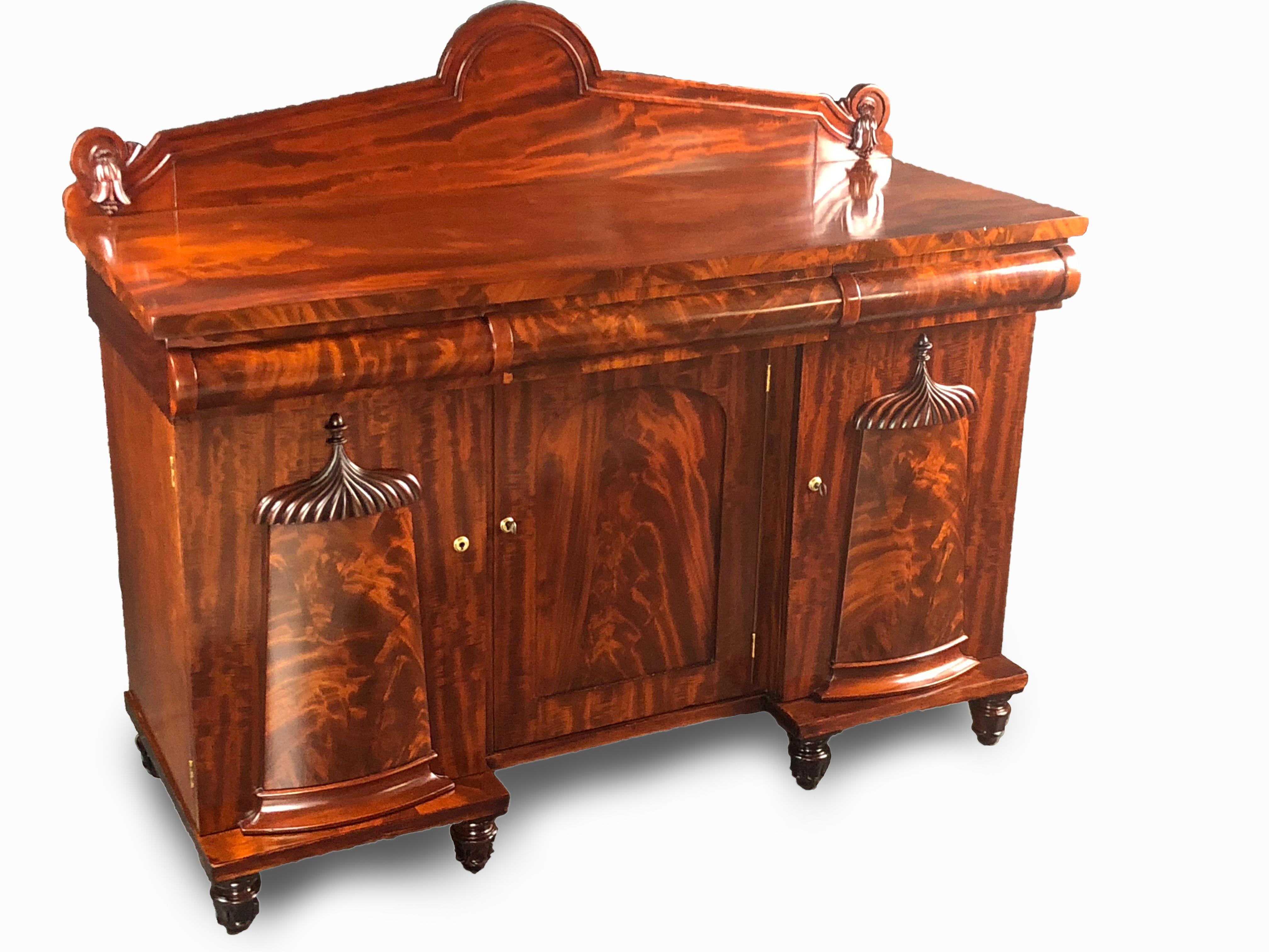 Exceptional Victorian medium size breakfront sideboard featuring unusual designs and carvings with exquisitely matched mahogany veneers. The removable backsplash with finely carved floral designs at each end. Below it, three mahogany round fronted