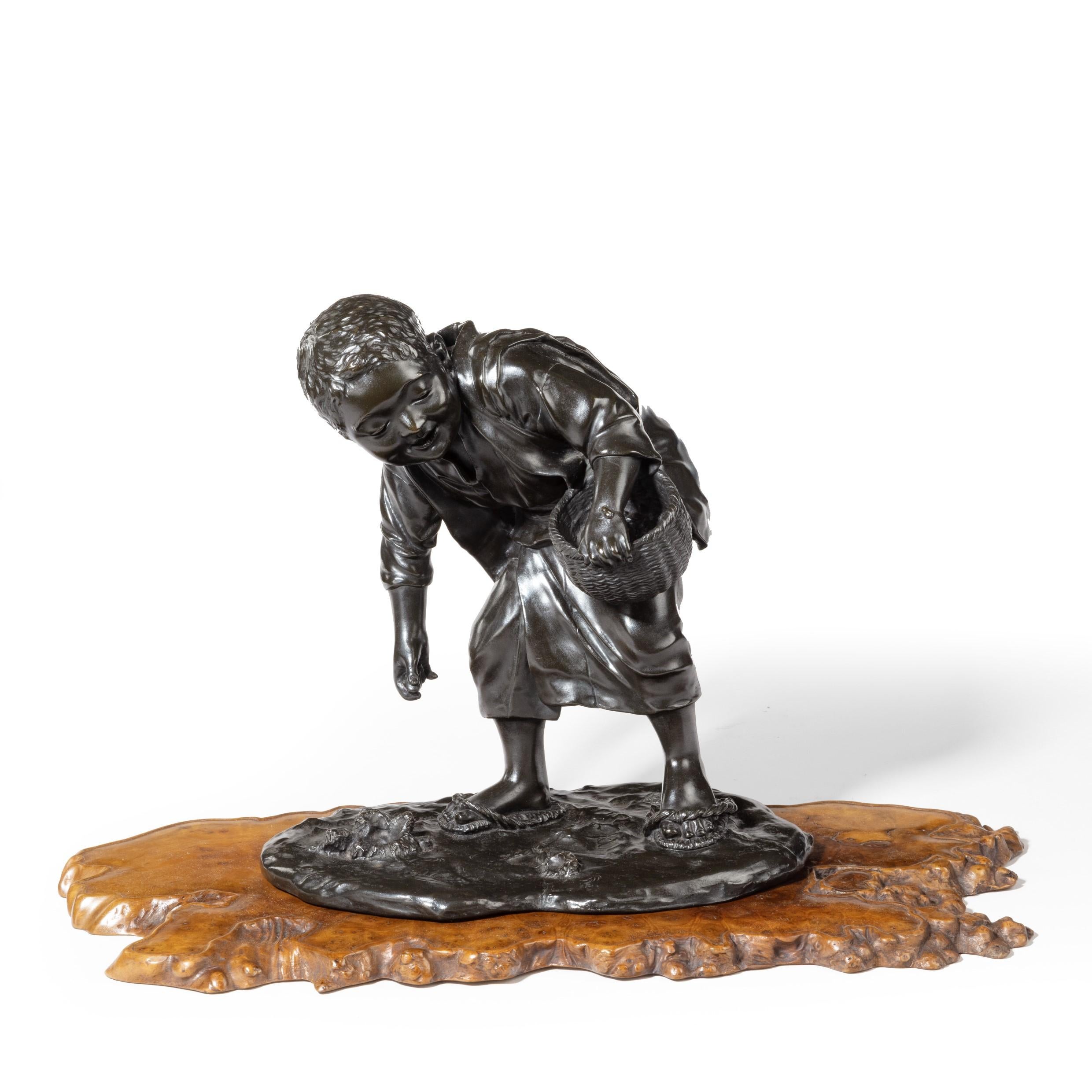A charming Meiji period bronze of a boy collecting sweet chestnuts by Seiya, he carries a basket and is looking down at an insect crawling over his hand, he is also evidently wearing adult sandals, signed in a seal ‘Genryusai Seiya zo’. Japanese,
