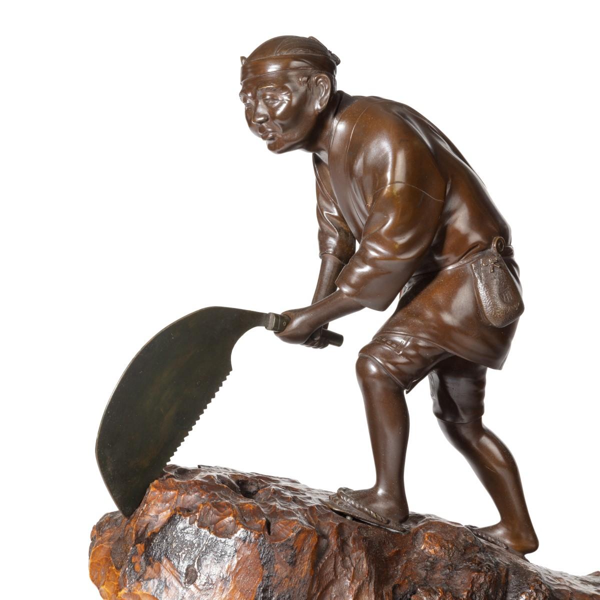An attractive Meiji period bronze of a woodcutter sawing a large tree trunk, he is standing on top of the wooden trunk, raised at one end on a trestle, and sawing with a large semi-circular toothed saw, wearing traditional clothing and with a pouch