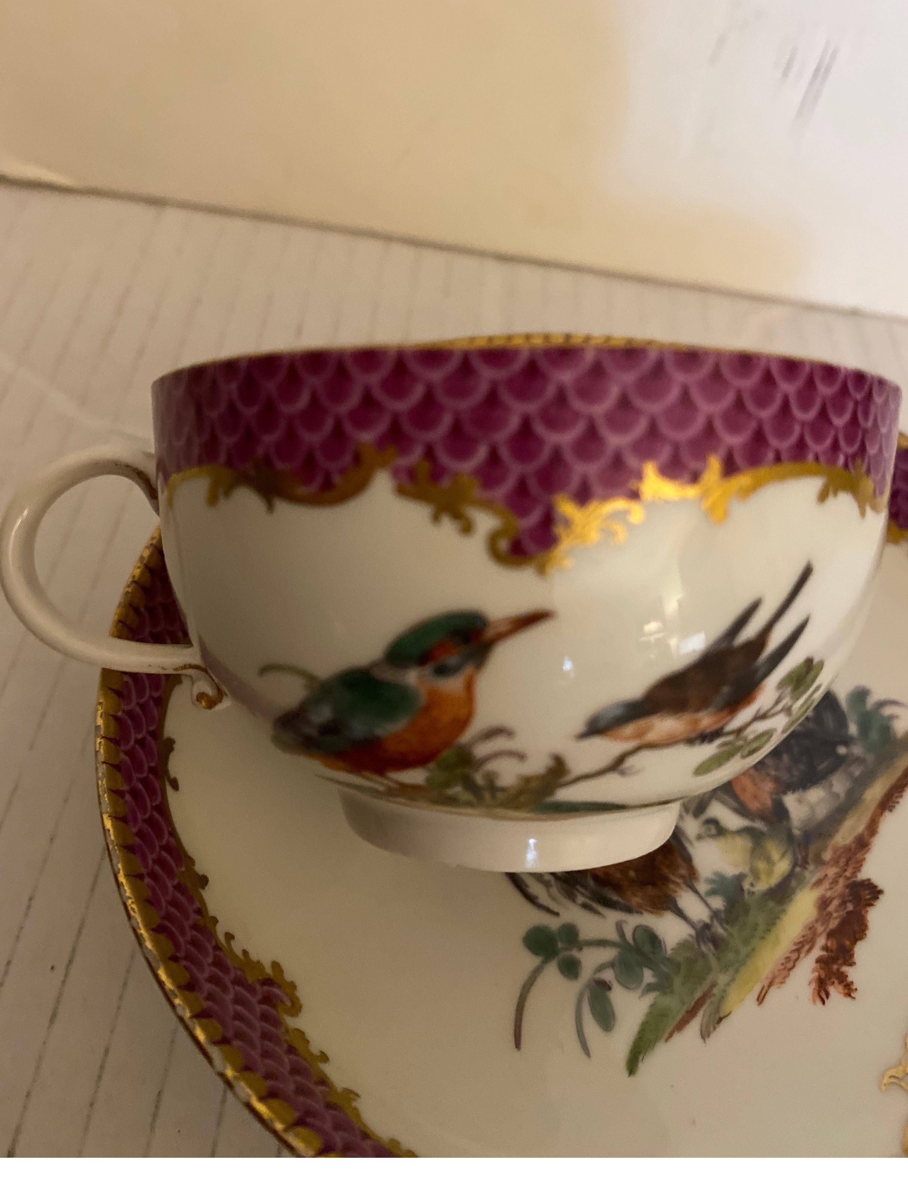 Petite tasse et soucoupe fantaisistes de Meissen du 19e siècle. La bordure violette à décor doré d'oiseaux et d'insectes. La soucoupe mesure 5 pouces de diamètre et la tasse 2,75 pouces de diamètre, sans compter l'anse.