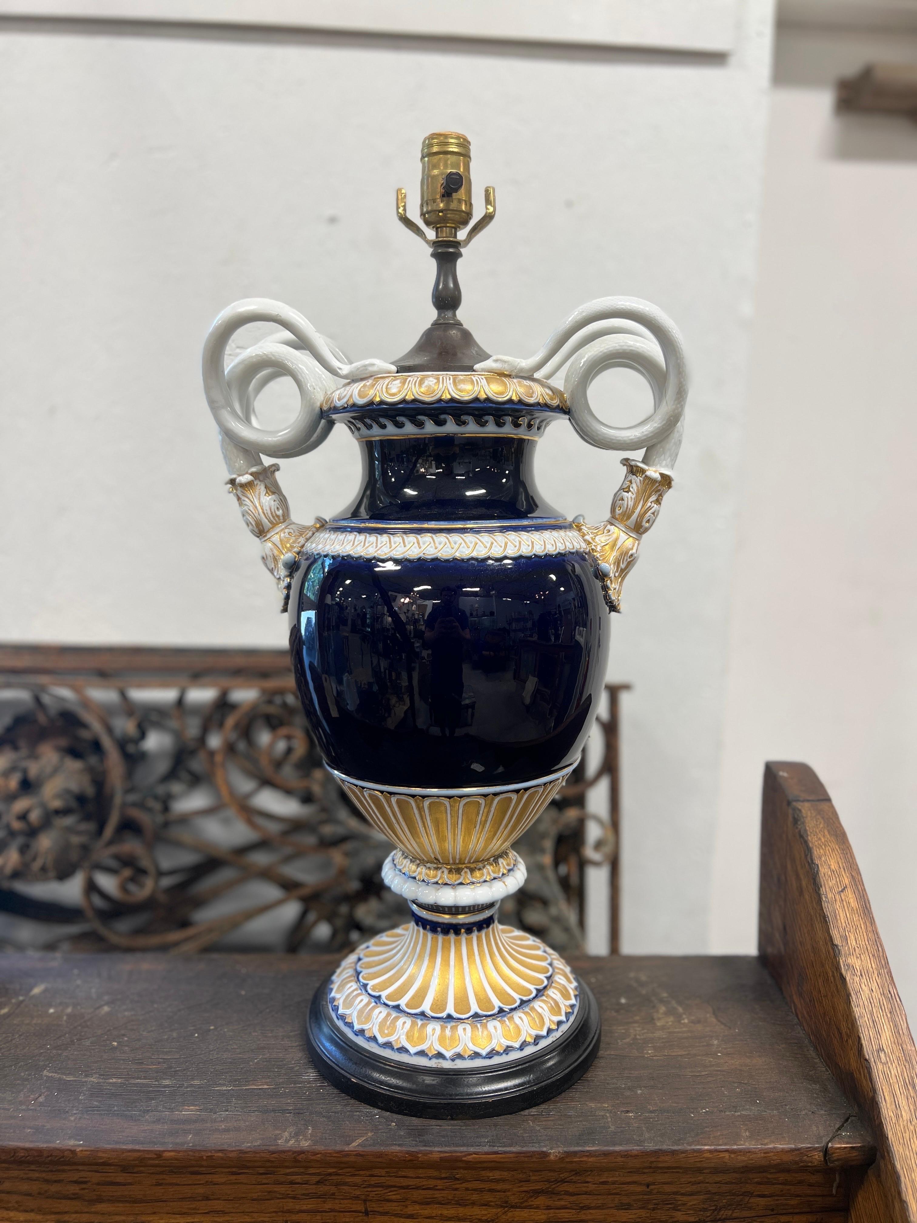 Meissen (German, founded 1710), circa mid 19th century.

This stunning antique Meissen urn has been converted to a table lamp. It features a Neoclassical baluster form with gilt and white gadrooned rim flanked by paired coiled serpent handles and