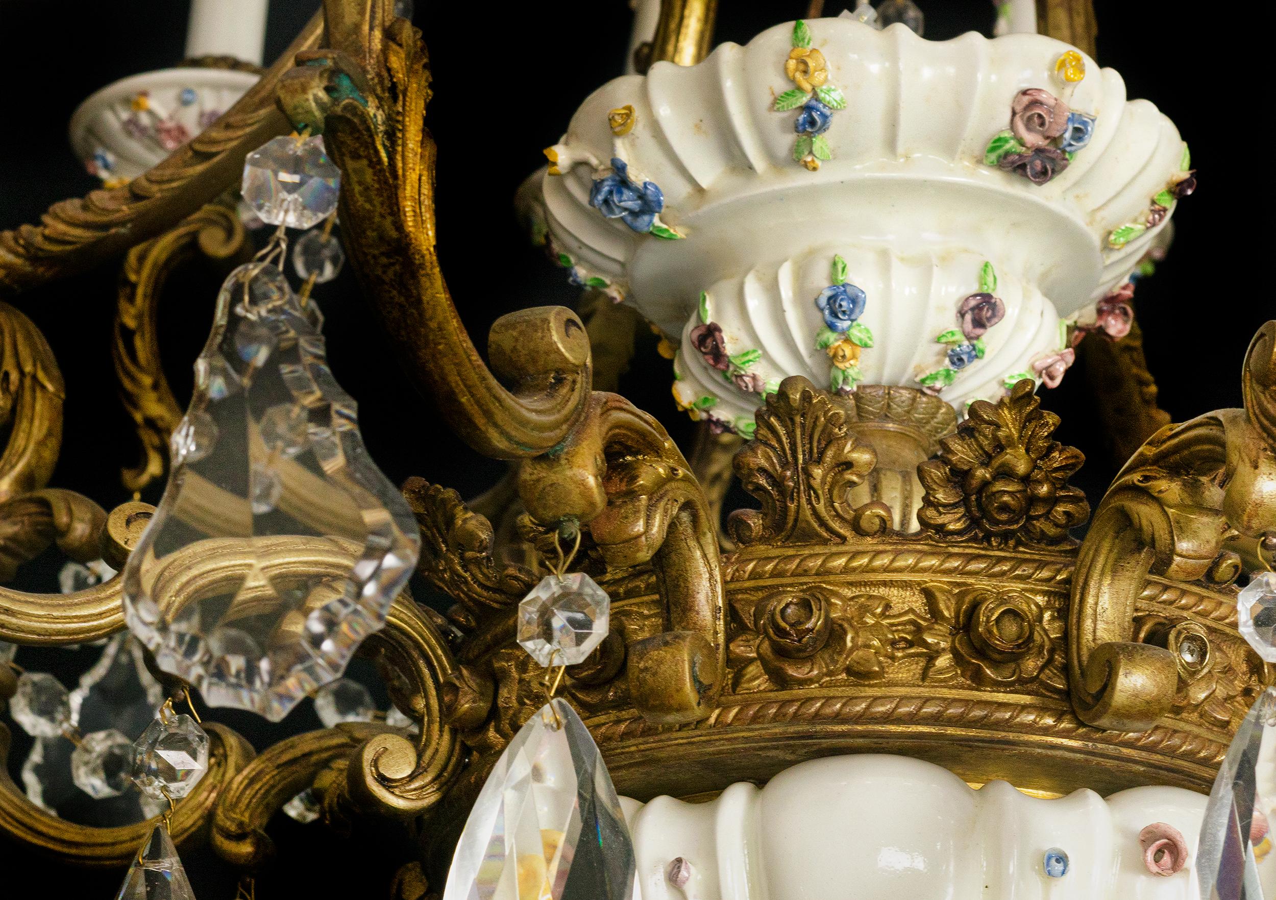 Ein großer, mit Blumen und Pflanzen verzierter Kronleuchter aus dem 19. Jahrhundert mit 16 goldenen Bronzearmen und hängenden Glasornamenten. 
Maissener Porzellan und goldfarbene Arme.

Die Elektroinstallation wurde kürzlich überprüft und
