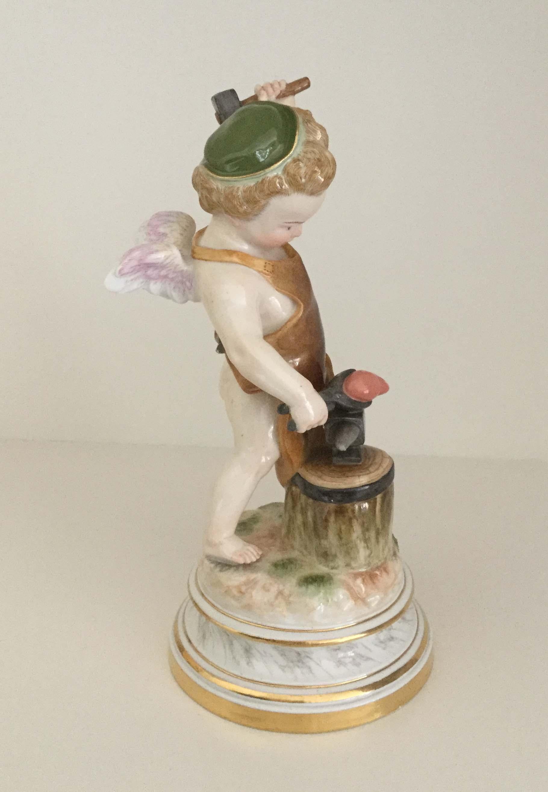 Meissen Porcelain figure of cupid forging a heart on a blacksmiths anvil which rests on a block of tree stump. The barefooted figure wearing a green CAP and dressed in a brown leather smock, mounted on a circular marbled base with gilt highlights,