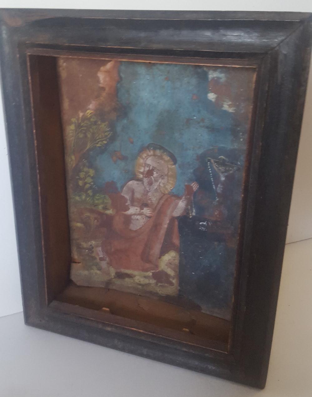 A Retablo painted on tin, in a period, wooden, black, shadowbox frame, missing its picture glass. The Retablo itself is in extremely distressed condition, missing paint, and an amount of imagery. Never the less, the subject of the work, St. Jerome,