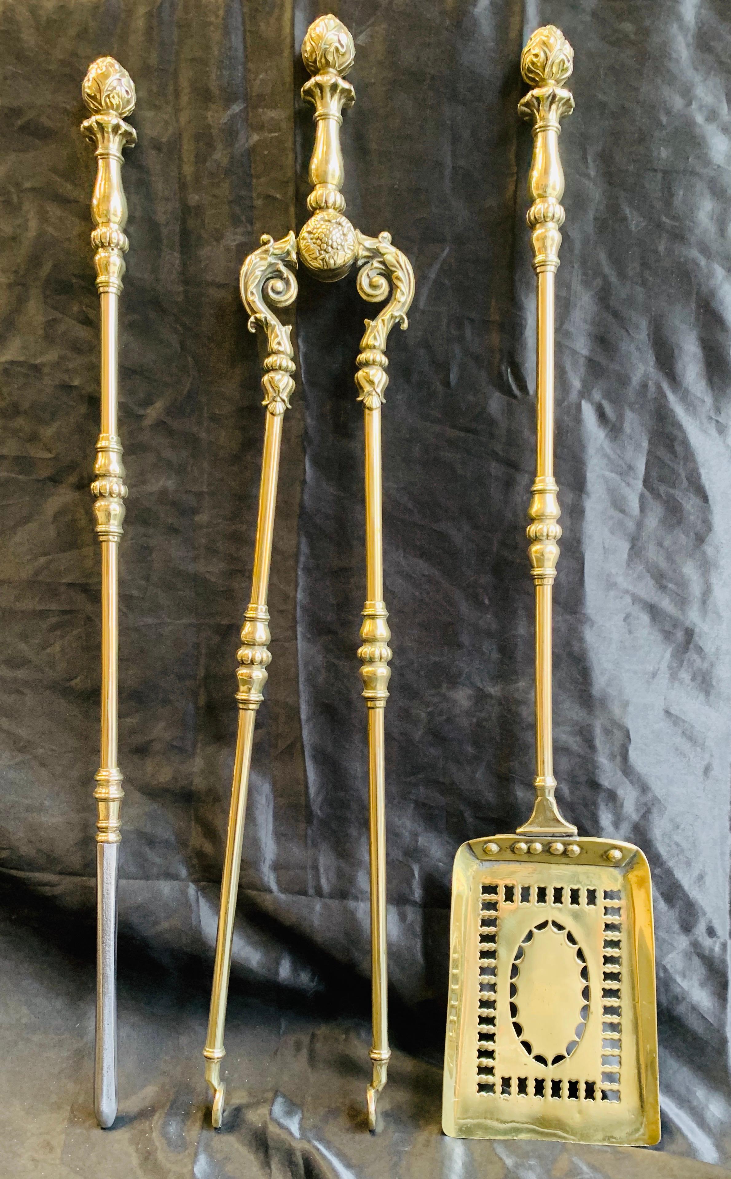 An ornate set of 19th century mid Victorian polished brass fire tools, comprising of a poker with steel end, a pierced shovel, and a pair of tongs all capped with acorn bud finials.

English, circa 1850.