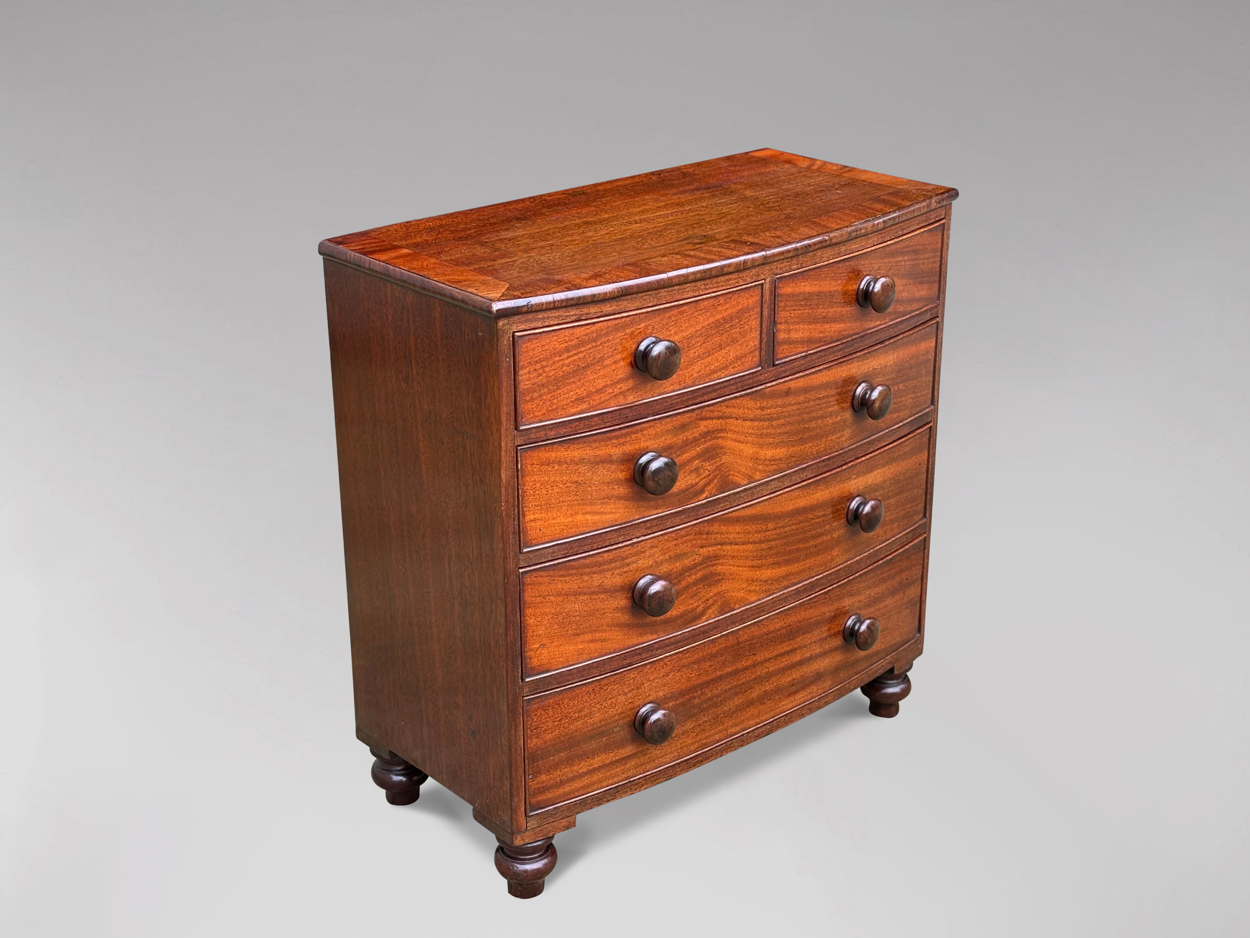 A mid 19th century mahogany miniature bow fronted chest of drawers, with moulded mahogany cross banded top, above two short over three long drawers, fitted with turned rosewood knobs. Raised on turned feet. Lovely colour mahogany and great