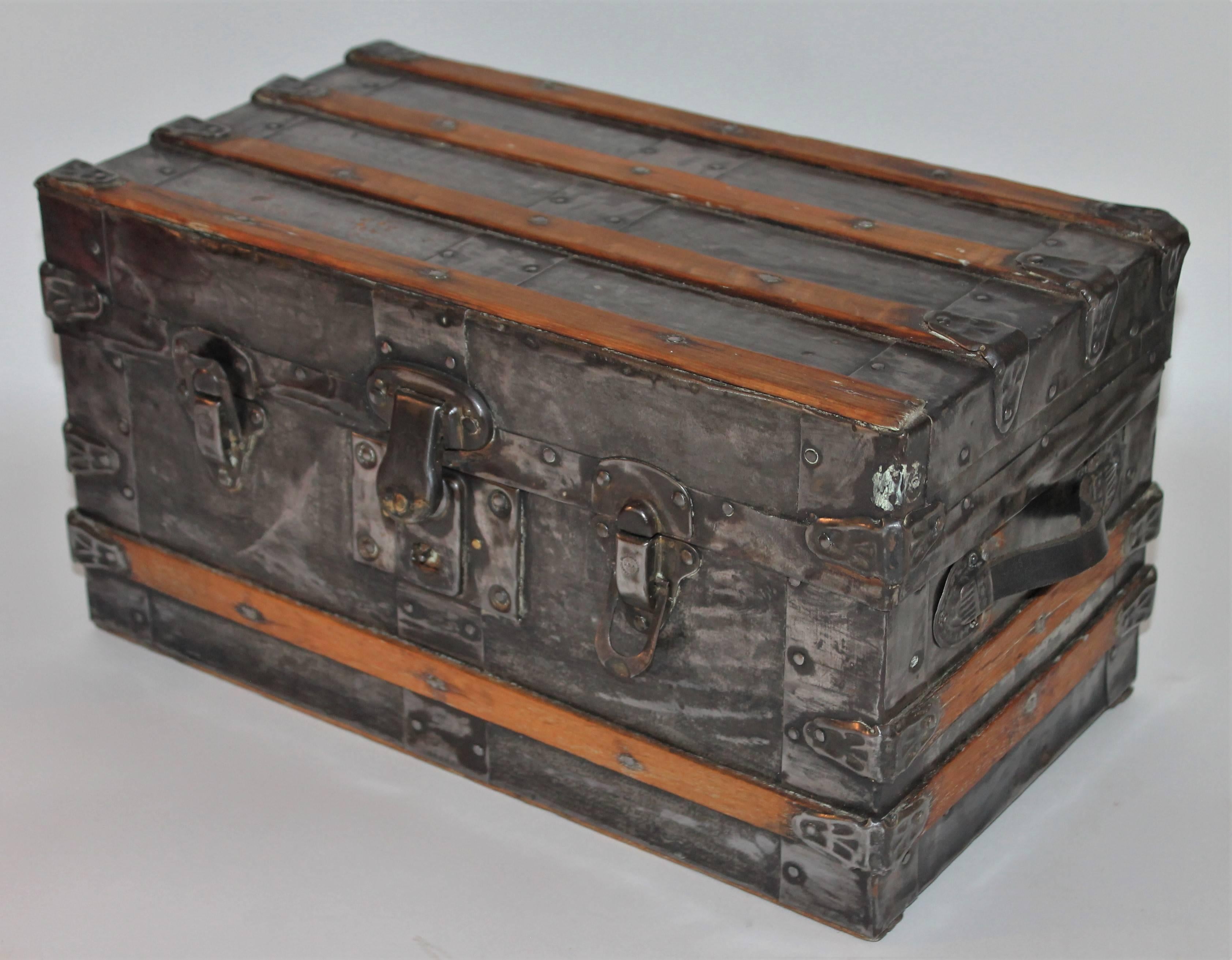 This 19th century small trunk would be great for a doll or teddy bear collection. It has a Industrial look with natural tin over wood and wood slated sides and top. It is signed Eagle Lock Co. USA / Terryville,Conn. on the metal closures. The