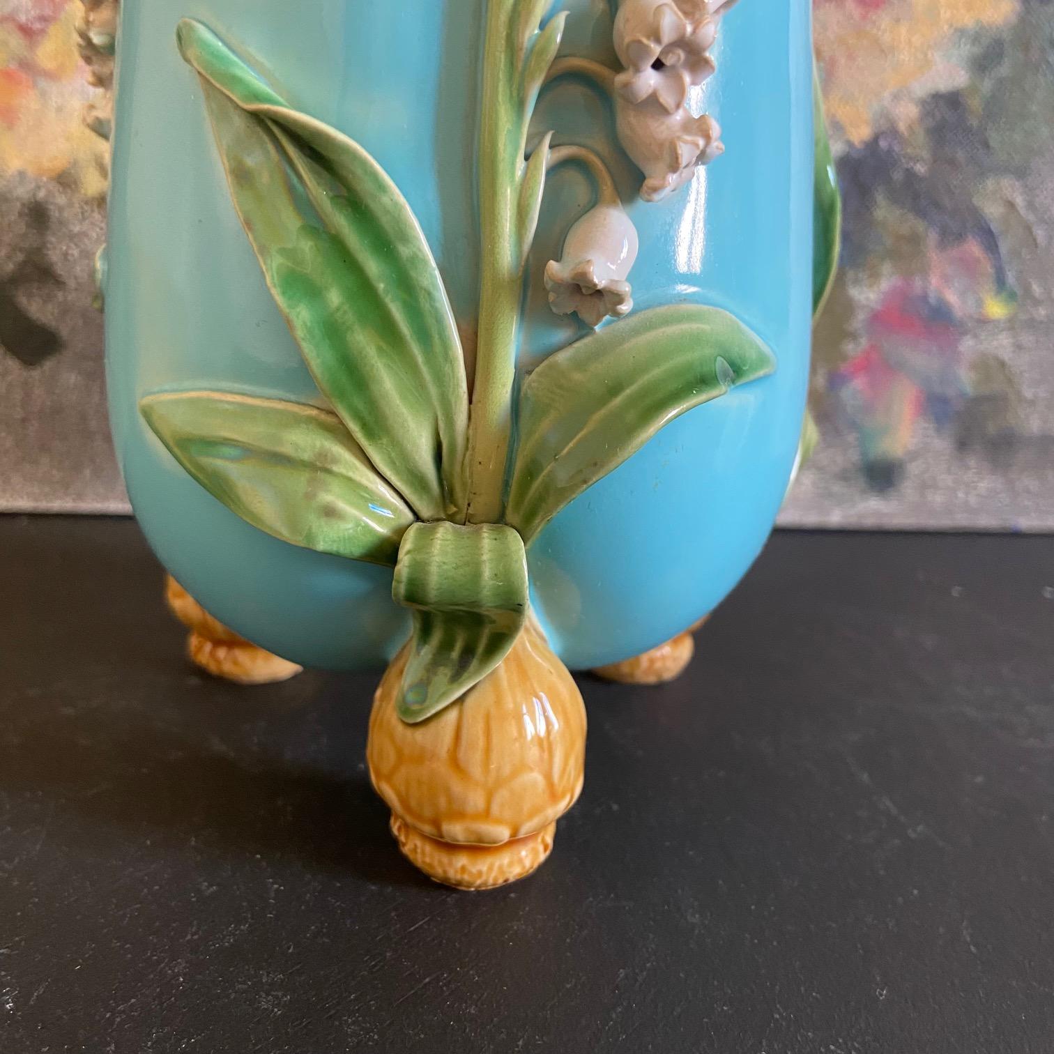 Piccolo vaso antico in maiolica di Minton, con disegno di mughetto e tre piedi a bulbo spuntati. Fondo turchese con gigli bianchi, foglie verdi e interno rosa. 
Porta i marchi del produttore Minton e la data cifrata è del 1860.

Un'opera molto