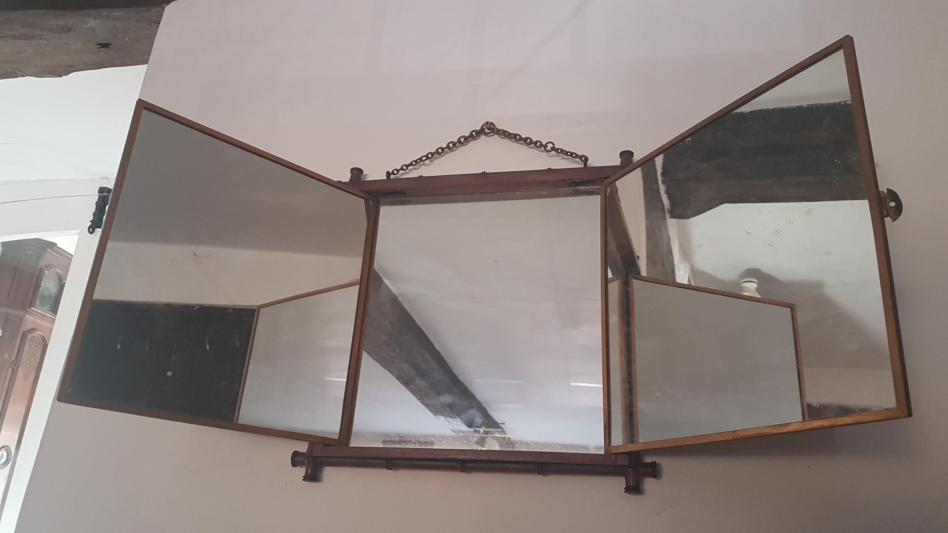 A tryptic mirror by the renowned Miroir Brot company in France. Miroir Brot invented, designed & patented this form of tryptic mechanism which at the time was very innovative. The mirror is contained within a decorative faux bamboo frame which is in