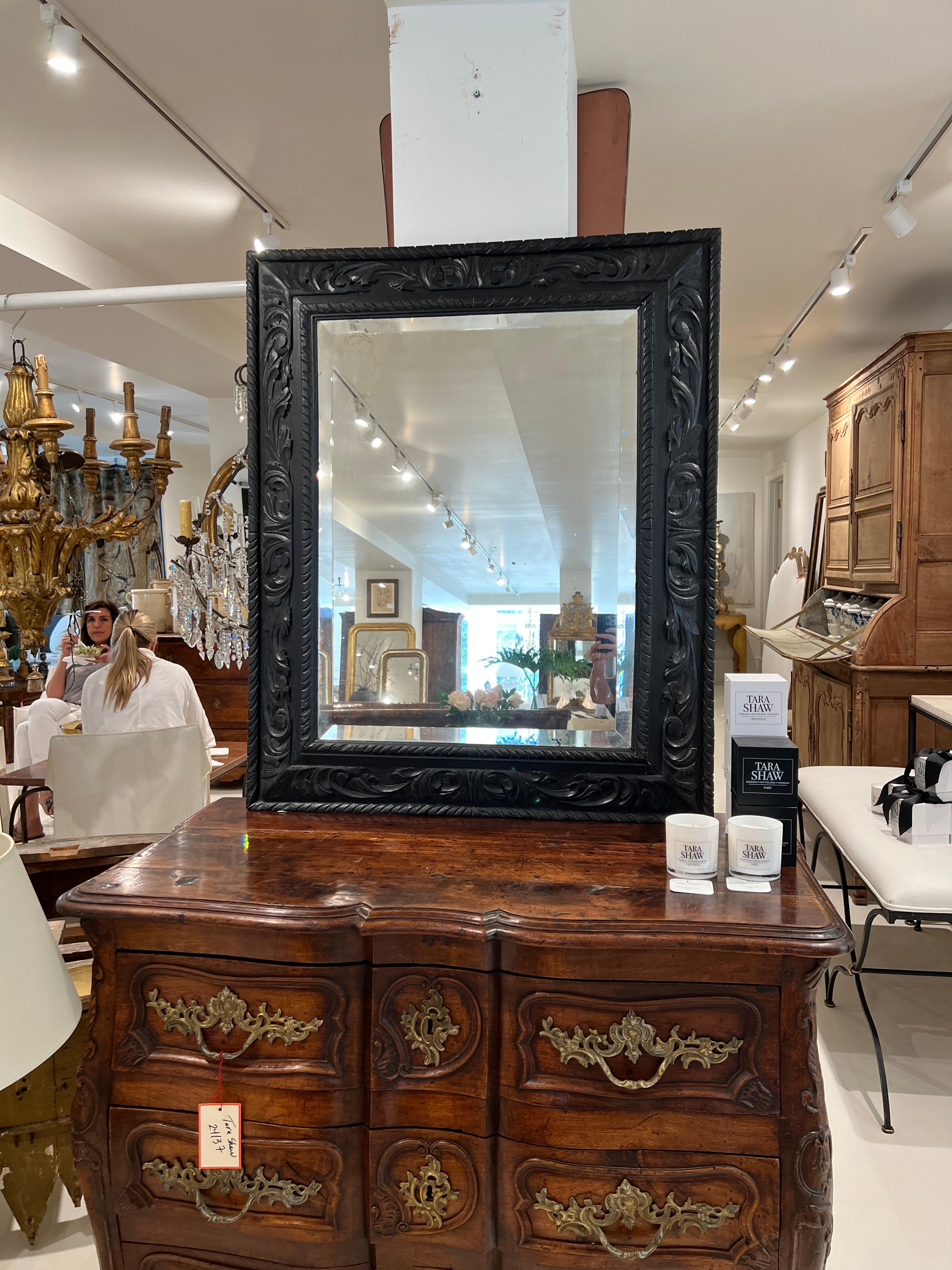 Very wide, heavily carved frame with a reversed cove toward the back.  Beautiful beveled mirror in original glass.  The impression of what appears to be a makers mark is visible in the upper left corner of the mirror.