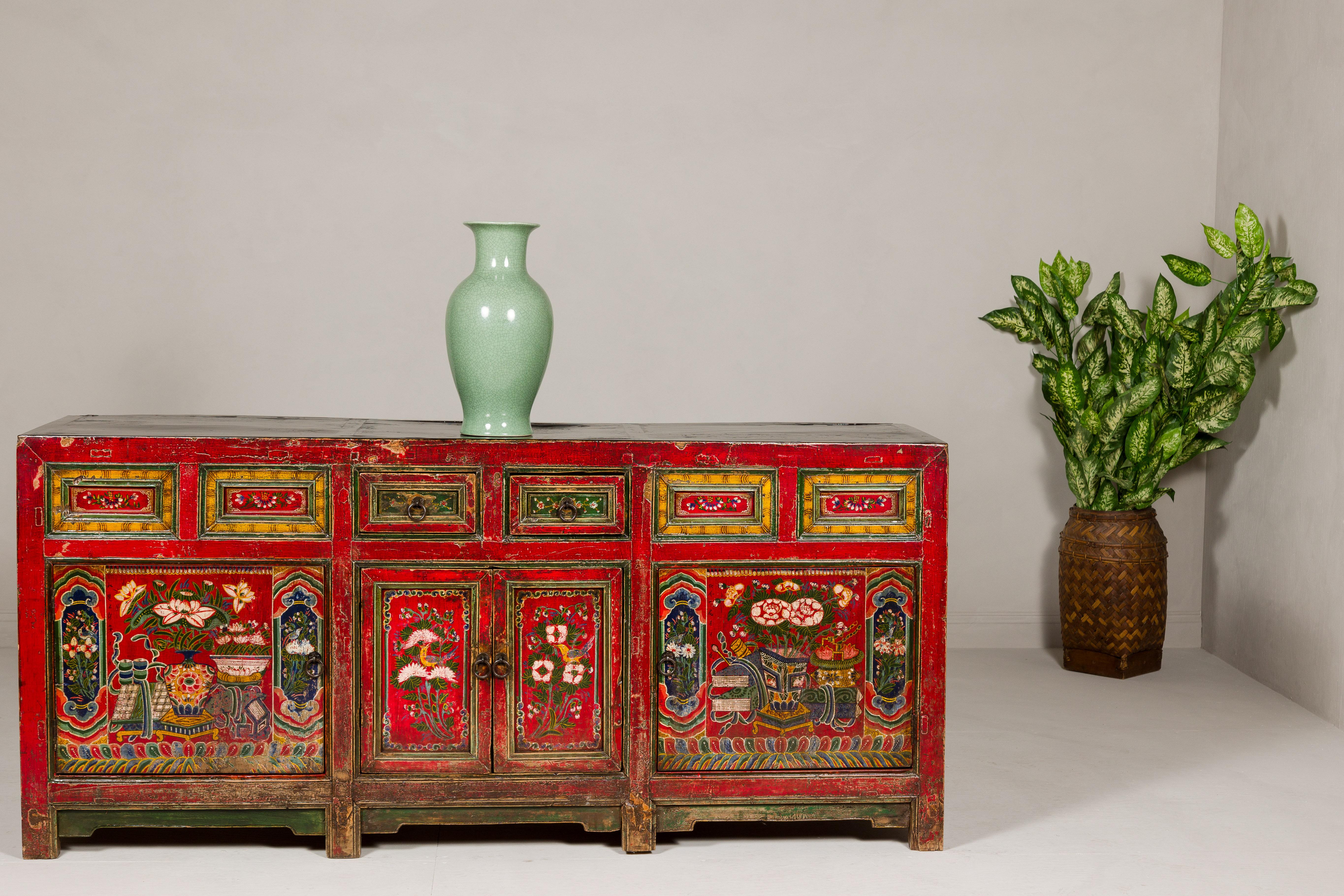 An antique Mongolian long polychrome sideboard with four doors and two drawers. This antique Mongolian long polychrome sideboard is a captivating fusion of form and function, rich in history and vibrant in aesthetic. Its striking red ground serves