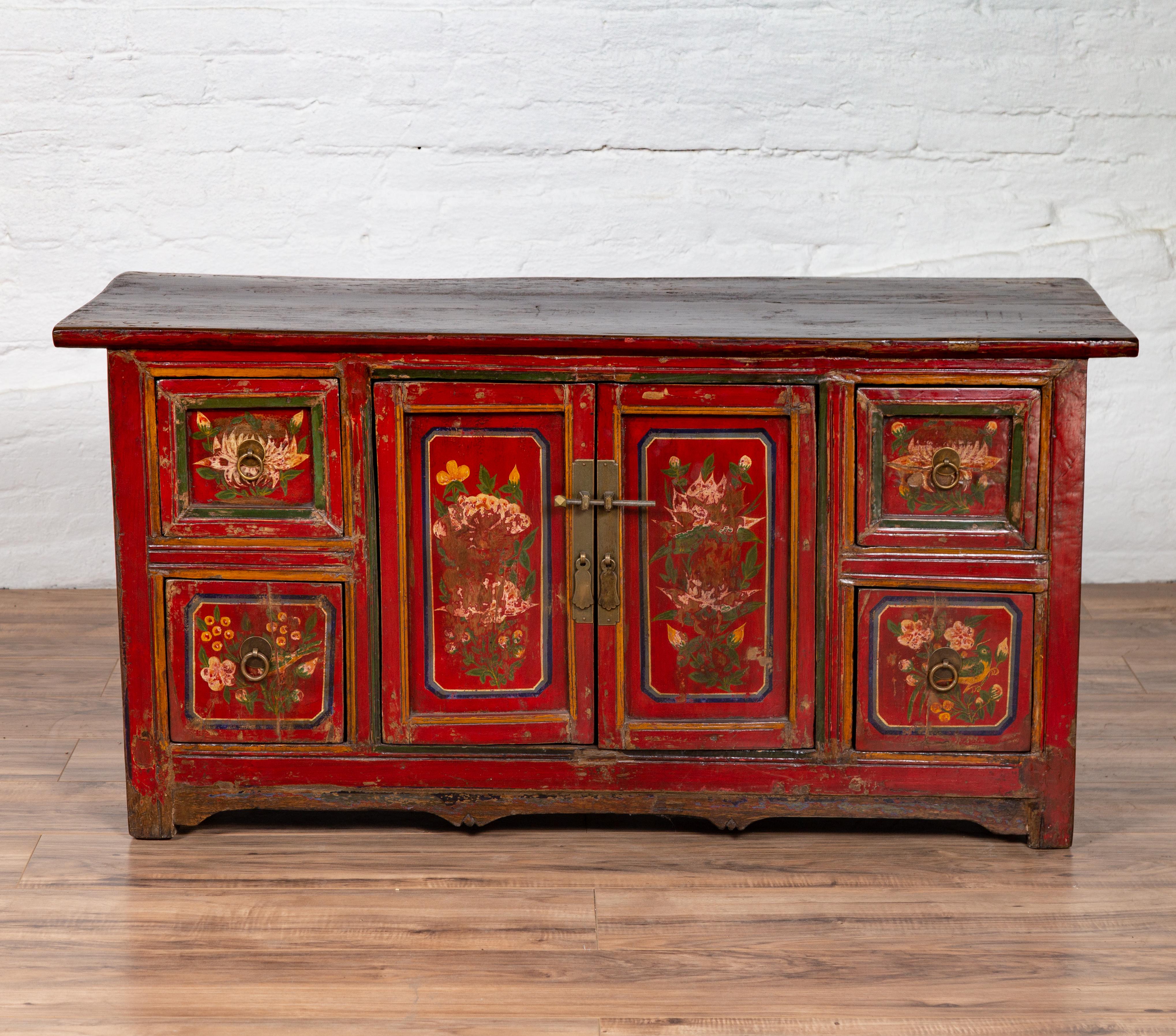 An antique Northern Chinese/Mongolian red lacquered cabinet from the early 20th century, with hand painted floral décor. Born during the early years of the 20th century in the Mongolian / Northern Chinese area, this exquisite cabinet features a