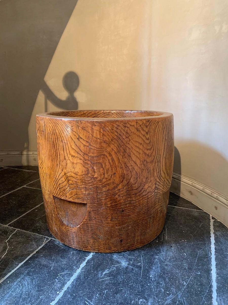 A large Chinese elm planter. The barrel shaped planter made from one solid piece of beautifully grained elm. Originally containers like this would have been used as measurement for grain. The incisions at the sides were for inserting a lifting