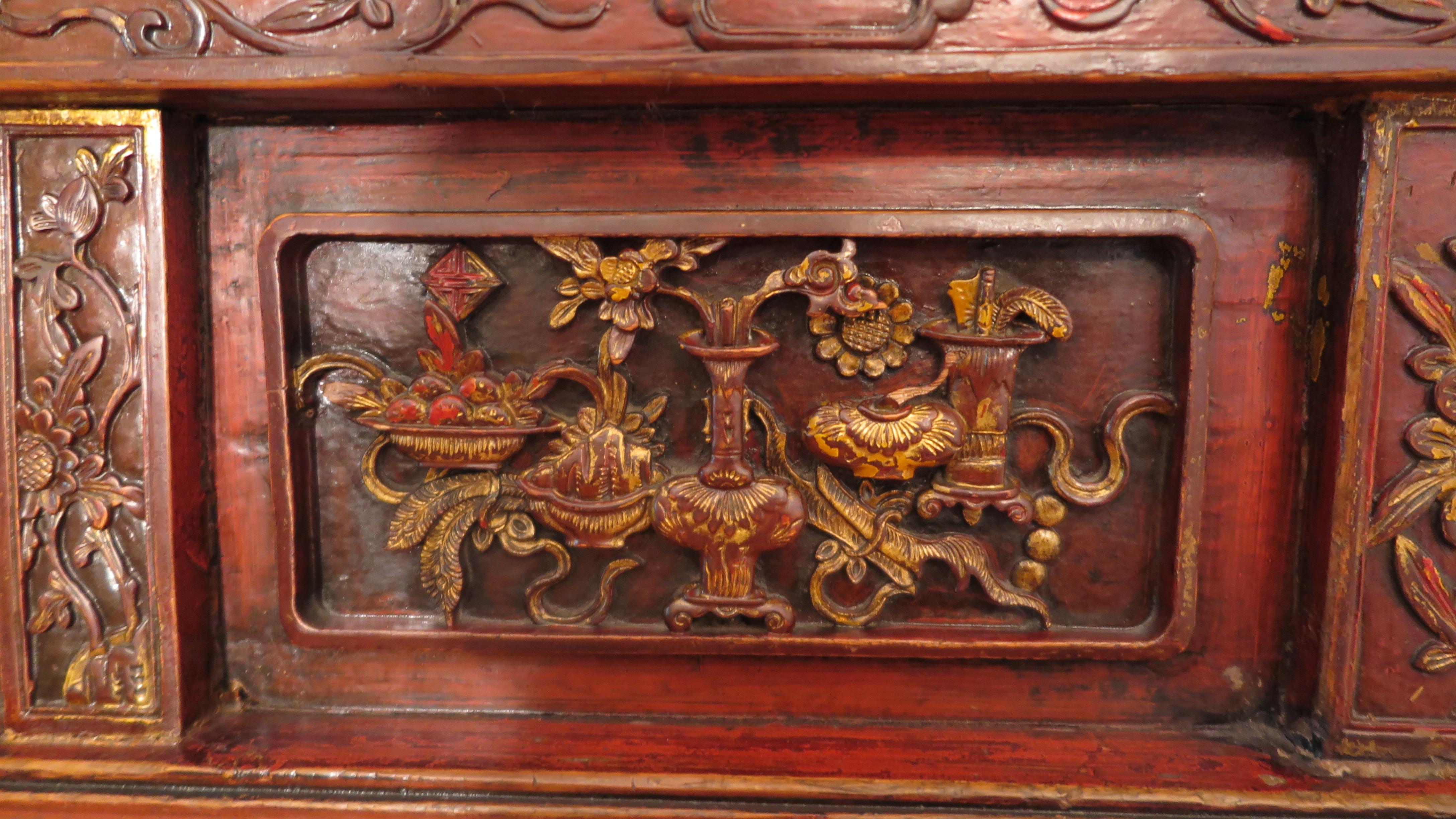 19th century carved gilded monumental Chinese Altar table. Five richly carved story board panels elaborate the apron with intricate carved figures showing through gilded red lacquer. Set underneath a solid one piece top plank with everted flanges of