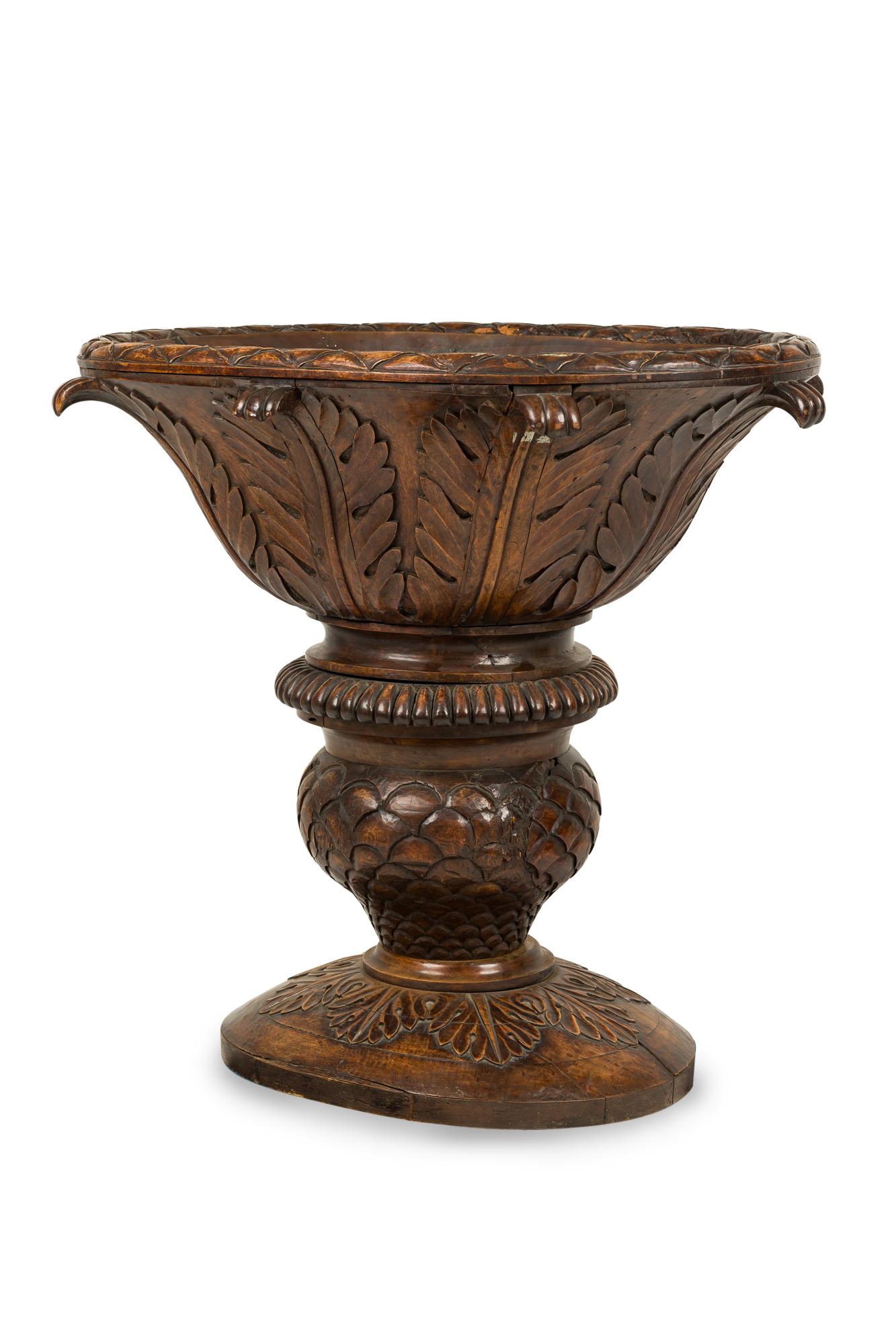 Monumental continental (19th century) carved walnut standing oval jardinière in the shape of a fluted cup with vegetal motifs. Interior lined in copper.