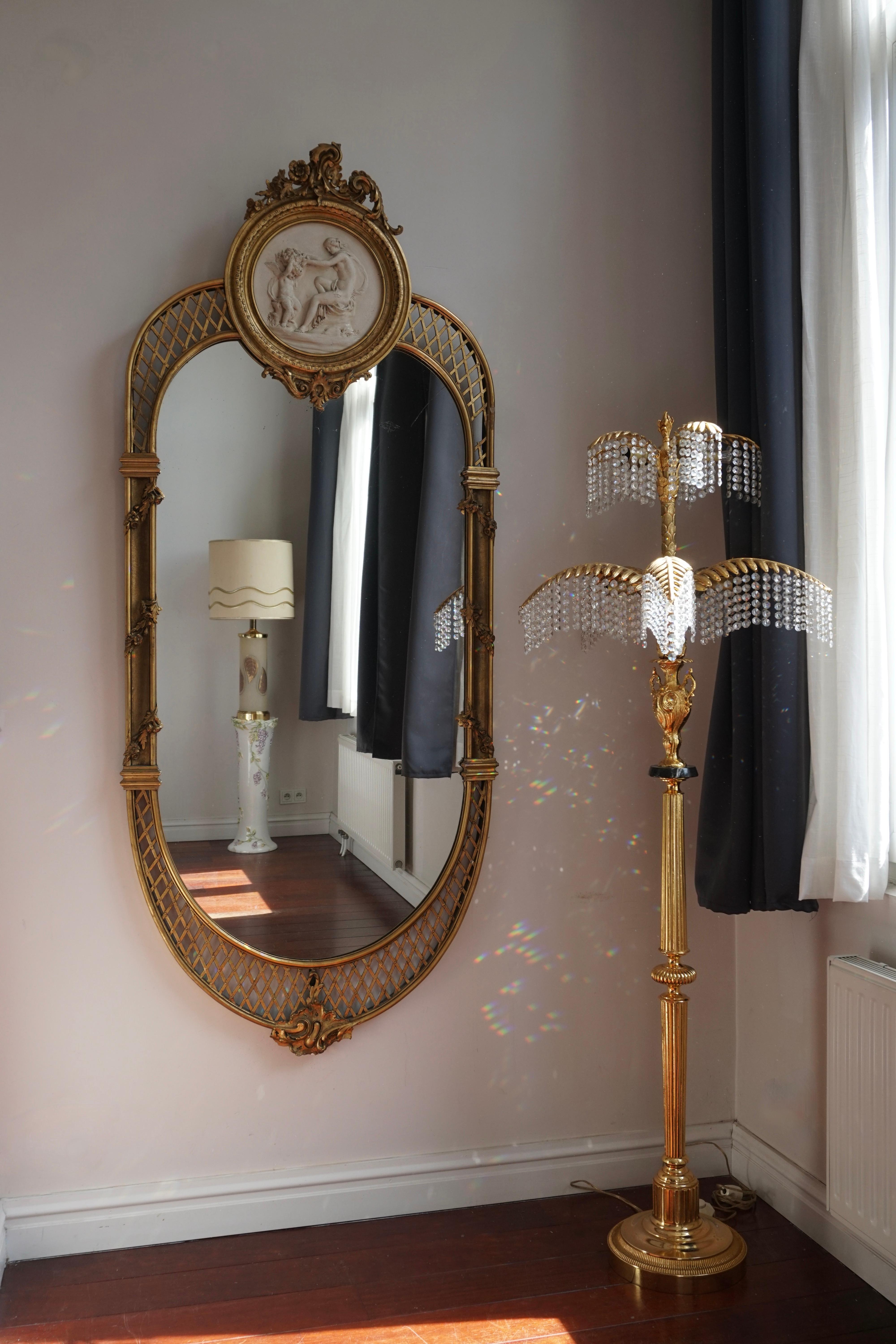 Miroir italien spectaculaire dans le goût rococo et de taille monumentale, fin du 19e siècle, doré et naturellement patiné dans sa finition d'origine, le miroir en forme de dôme surmonté de Putti en grisaille, de rinceaux, de feuillages, de patera