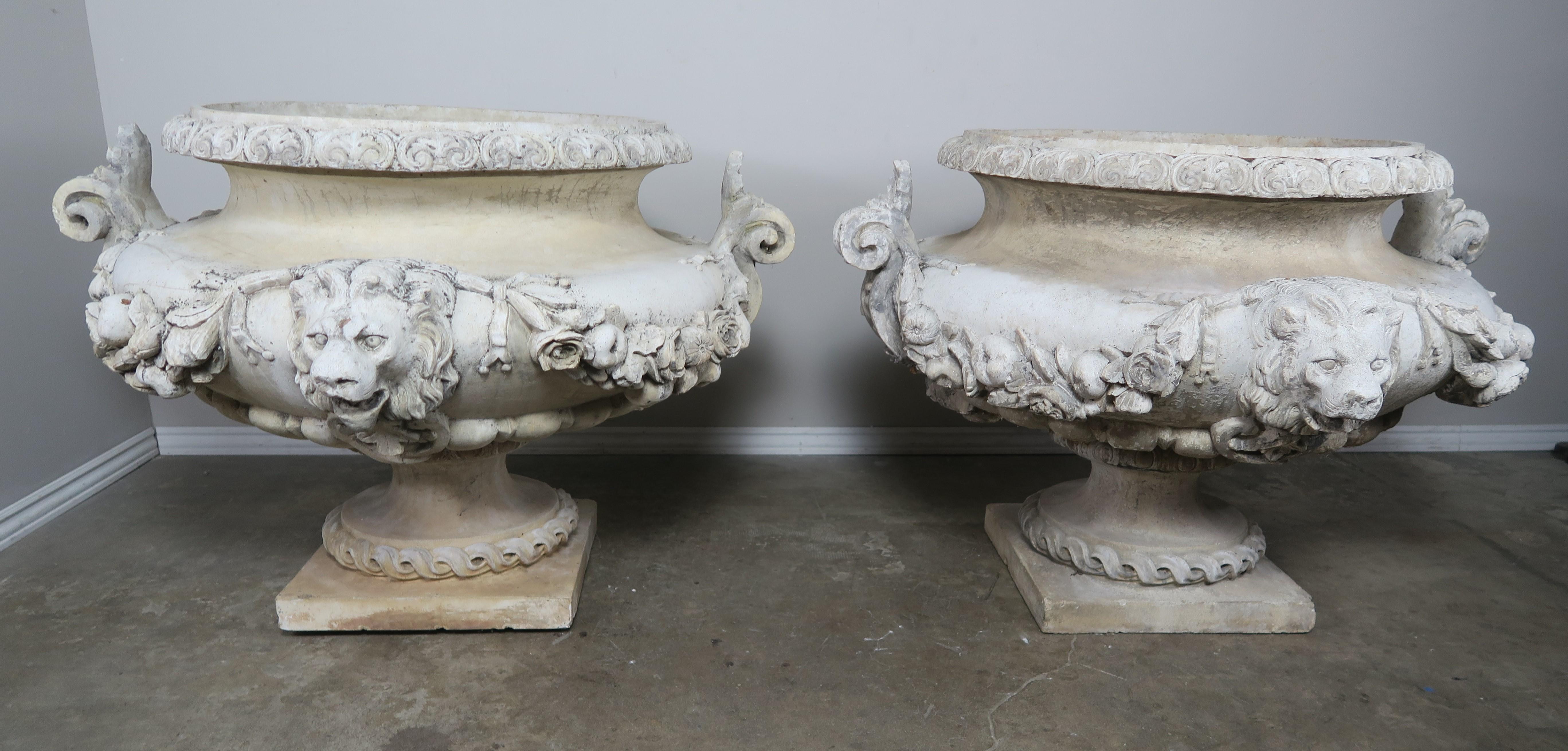 Pair of 19th century monumental Italian terra cotta planters with lion faces and garlands of fruit and flowers.