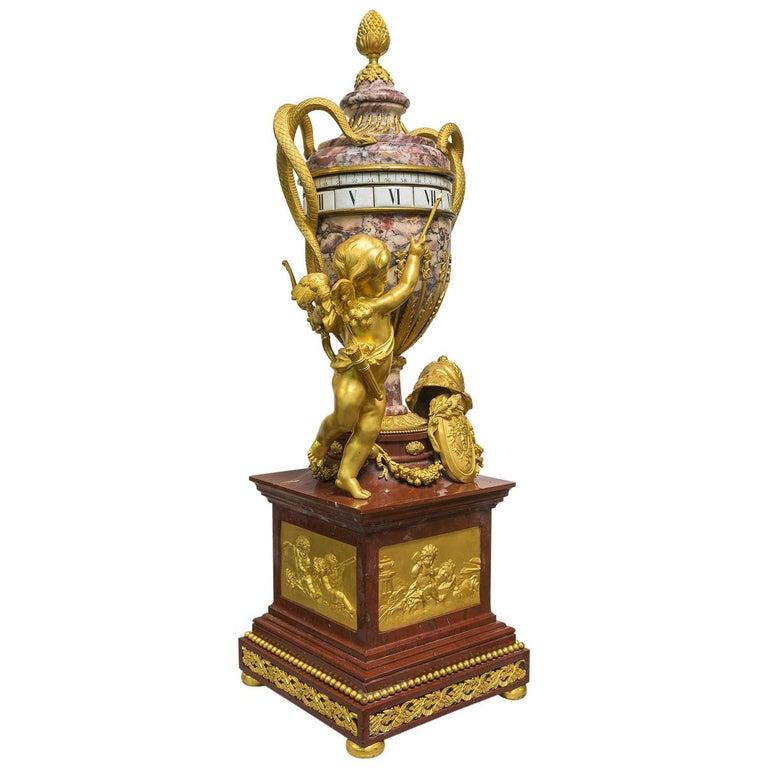 A monumental Louis XVI style ormolu mounted and rouge marble rotary mantel clock. A stunning monumental Louis XVI style gilt bronze mounted and rouge marble rotary mantel clock in the manner of Jean-André and Jean-baptiste Lepaute. The urn embellish