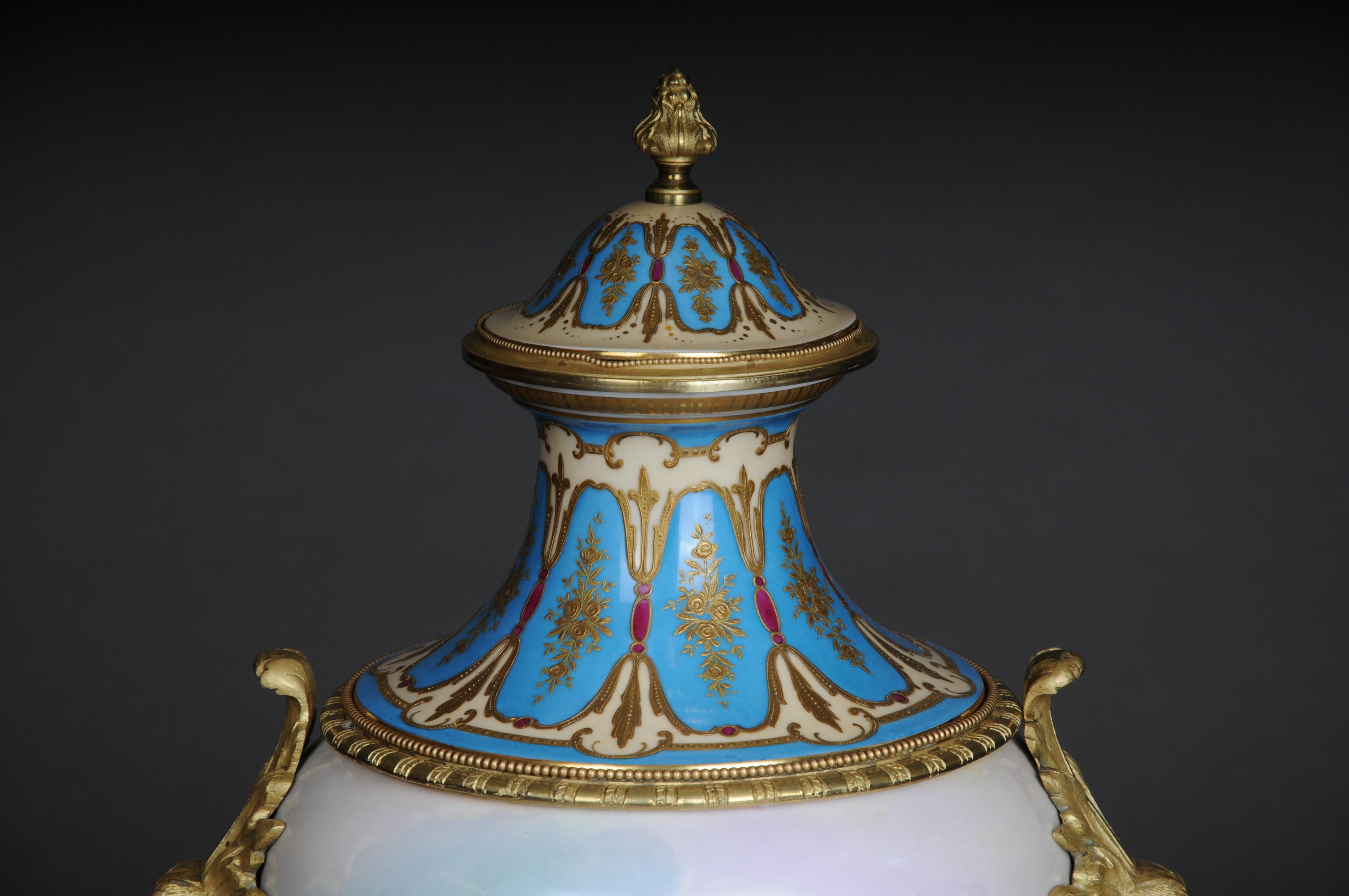 19th century monumental Sèvres pomp vase with bronze mounting

France, around 1890
Two-piece with lid. Bronze mount with a square stand, lateral women's masks and a small cone crown. Partly powder blue background with relief gold and red enamel.
