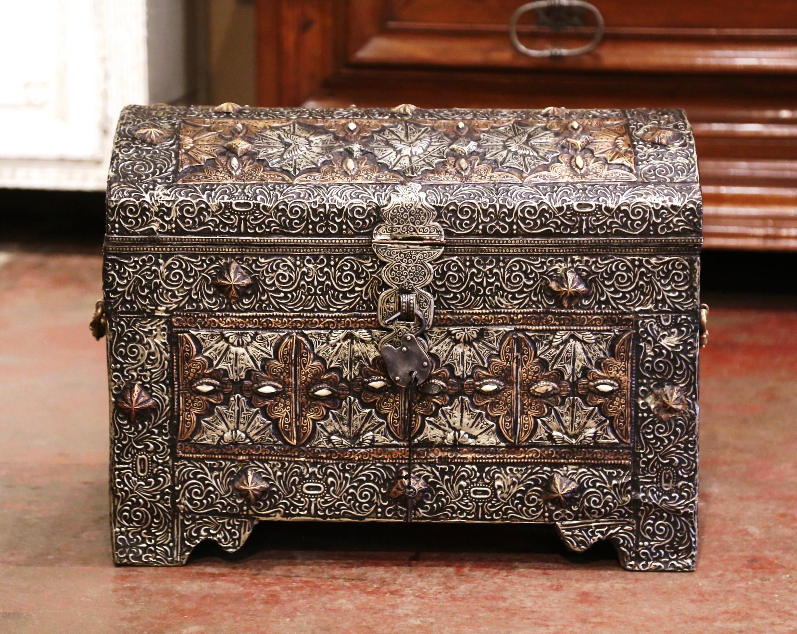 Cet élégant coffre ancien a été fabriqué au Maroc vers 1850. De forme bombée et construit en bois avec du cuivre, le coffre, avec des poignées latérales en bronze, est décoré de motifs en repousse partout, y compris de grosses têtes de clous