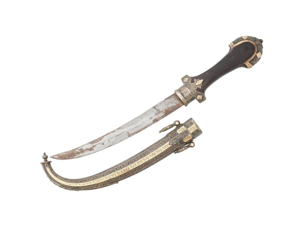 An antique Moroccan Berber Jambiya silver and gold mounted dagger. Circa the late 19th century. The shaped grip is encased in finely worked silver and gold chiseled and chased scrollwork and geometric motifs cover the surface. The blade of typically