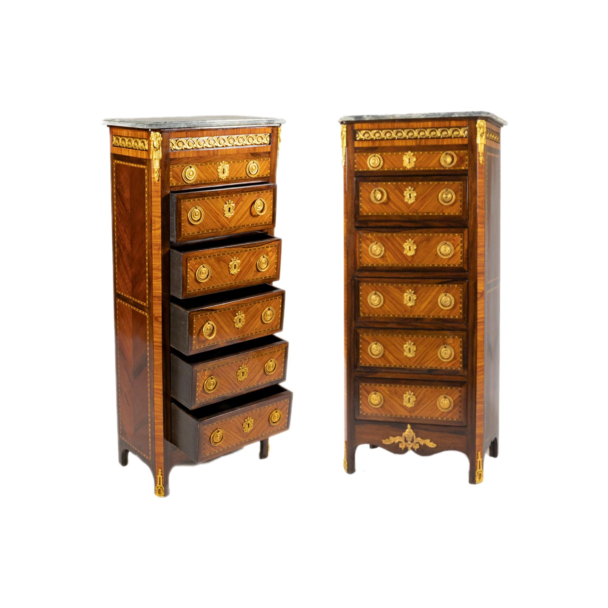 A 19th Century Transitional Style Five-Drawer Chiffonier with marble top and gilded bronzes mounts, handles and marqueterie of the chest of drawers canted with bronze corners, paneled sides with matched parquetry. 
It stands on very small legs,